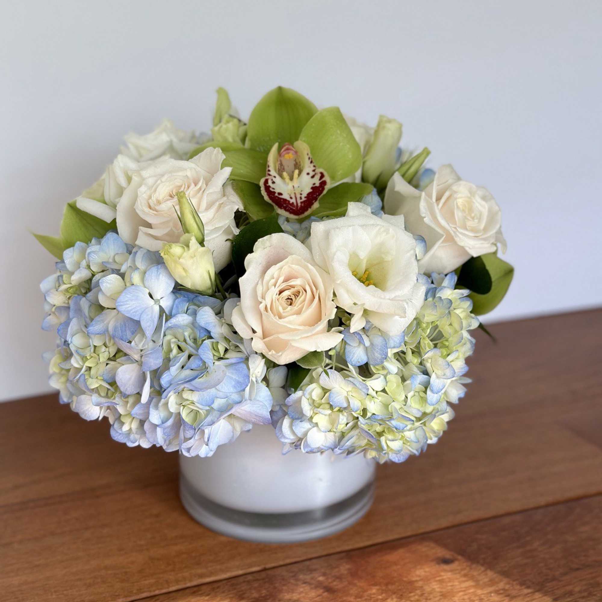 White and pale blue flowers arranged in a low glass vase