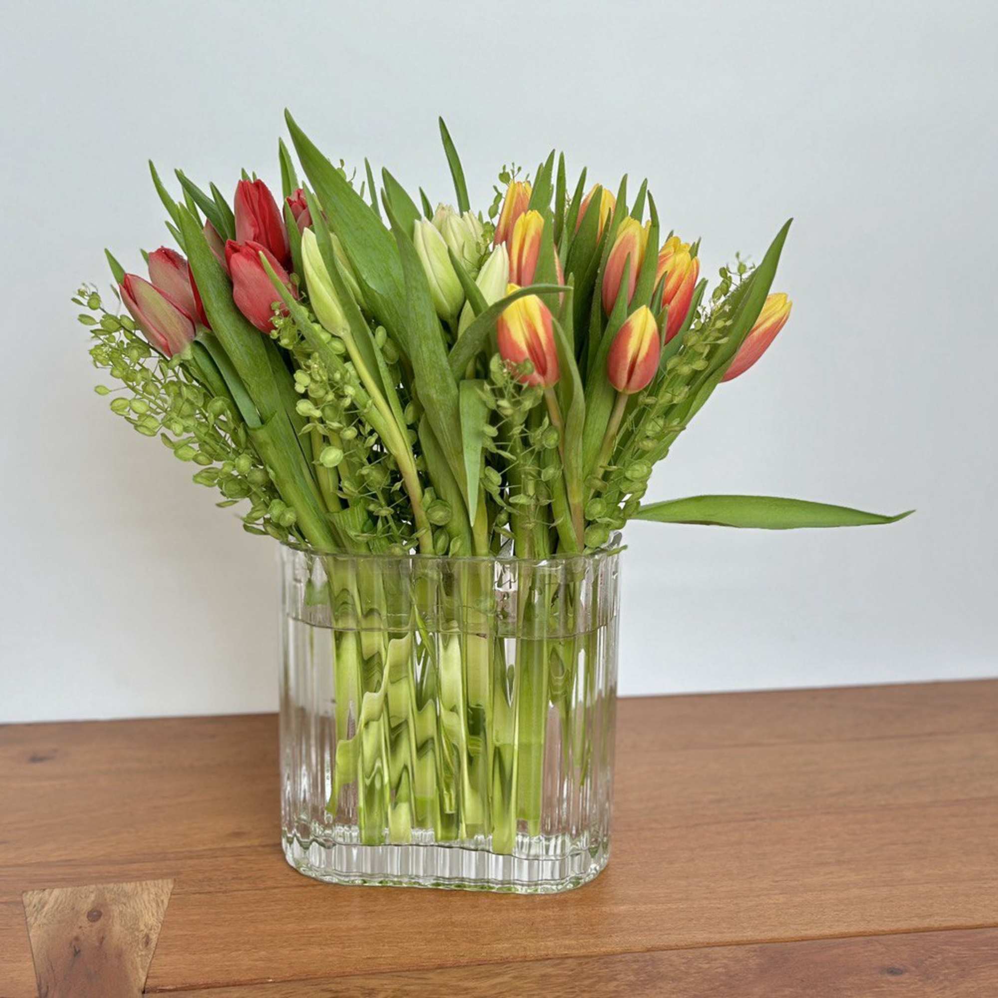 Bouquet of red, yellow, and white tulips in a clear glass vase