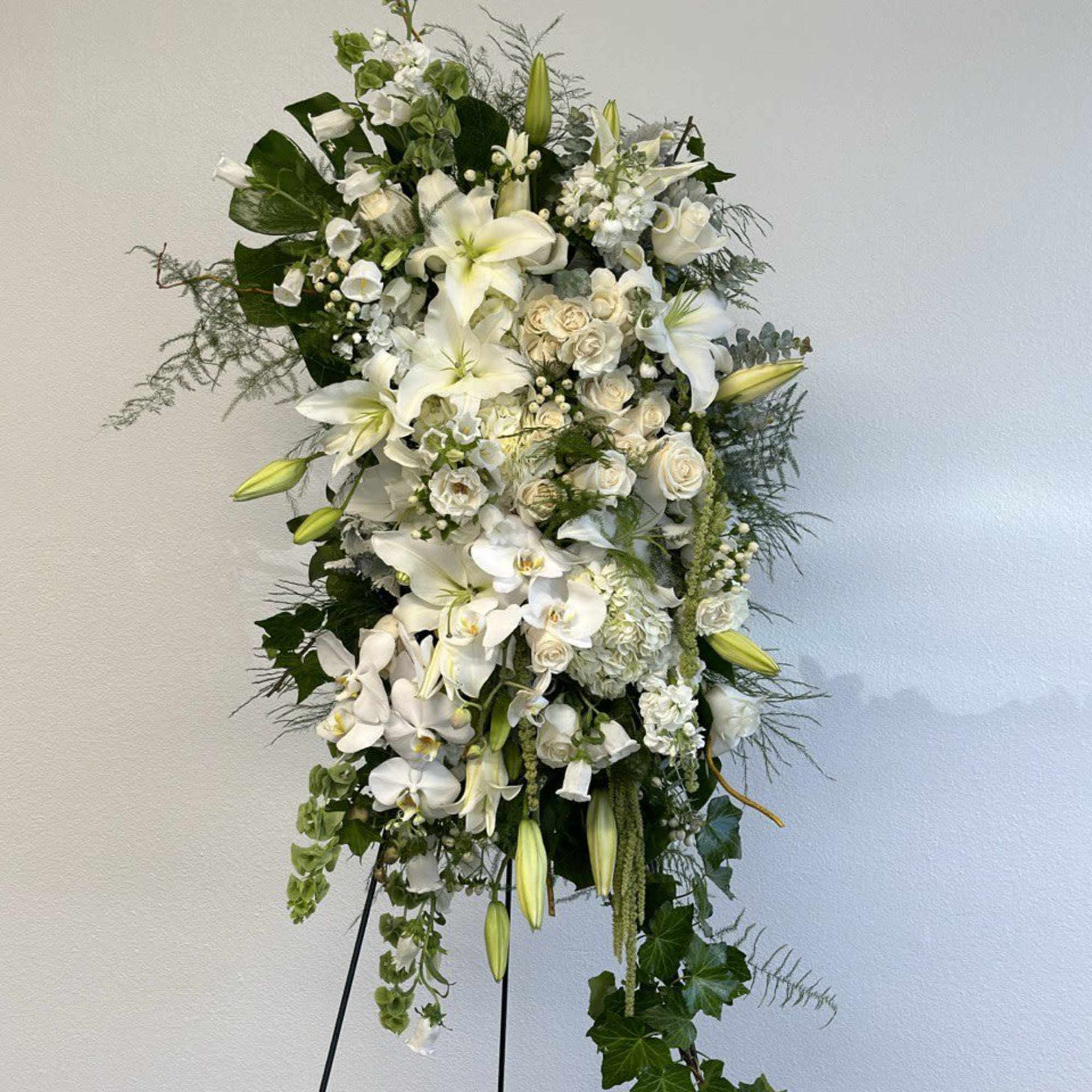 Tall white floral standing spray on a black easel