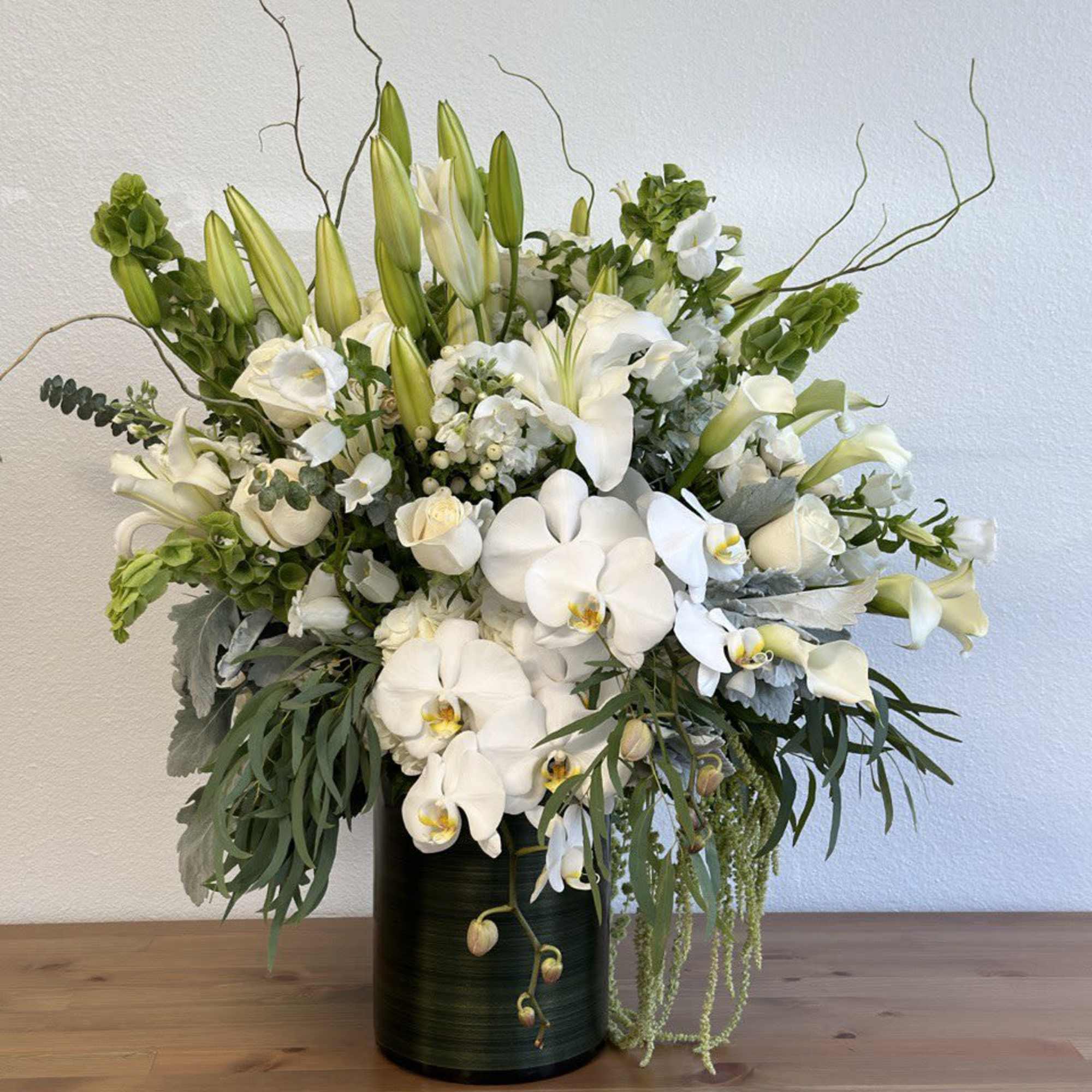 White orchids and lilies arranged in a dark vase