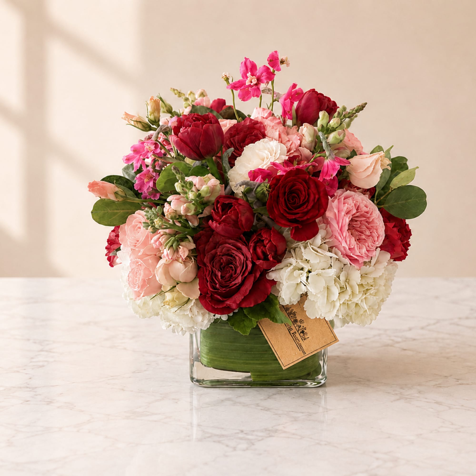 Mixed bouquet of red, pink, and white flowers in a glass vase