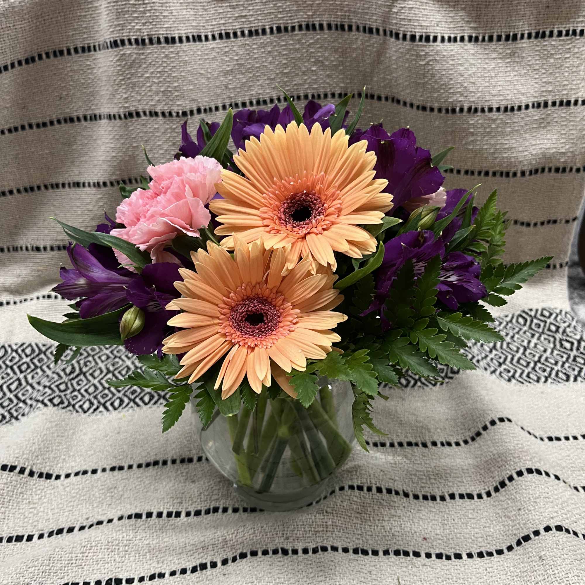 Bouquet of peach gerbera daisies and pink carnations in a glass vase