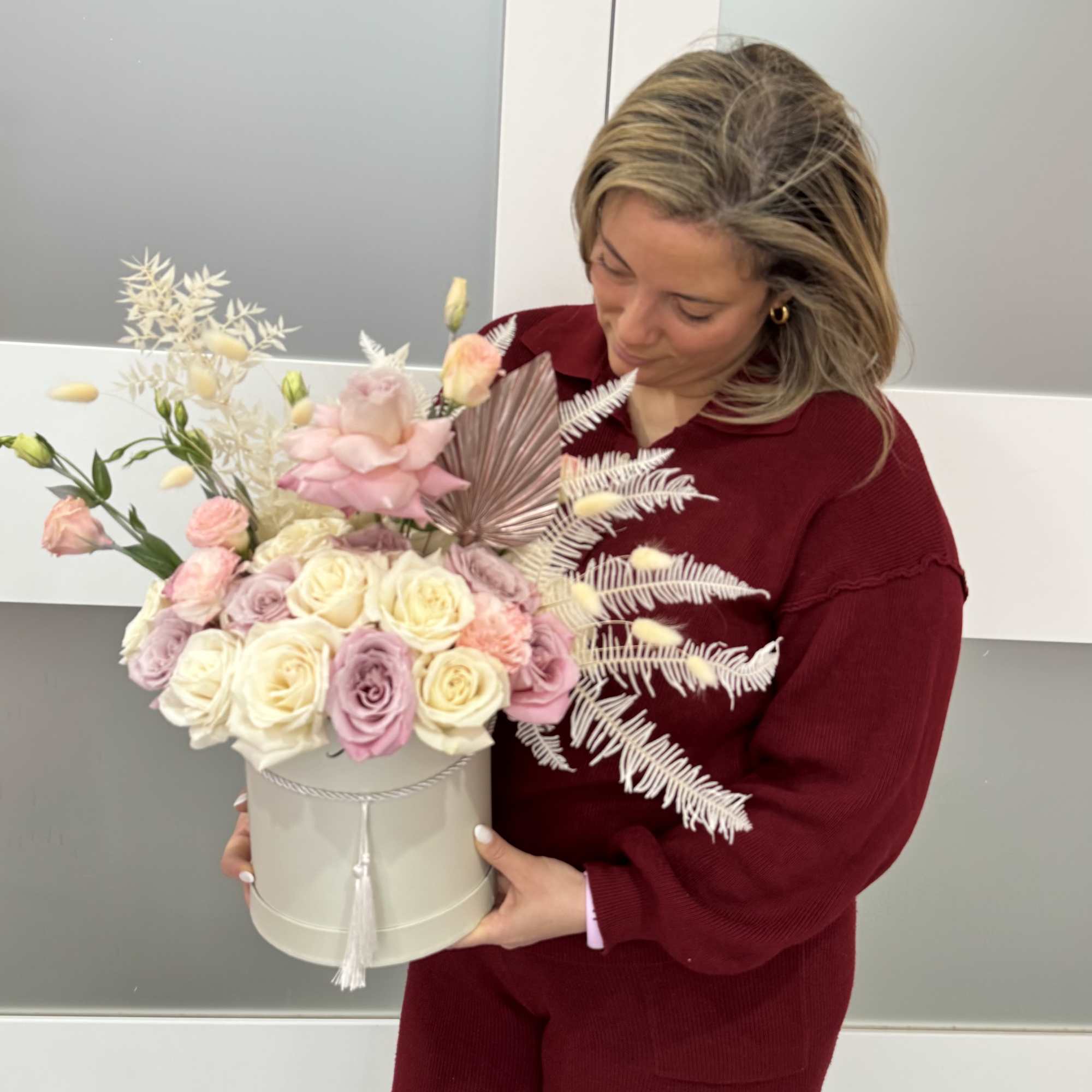 Woman holding a pastel rose arrangement in a round box