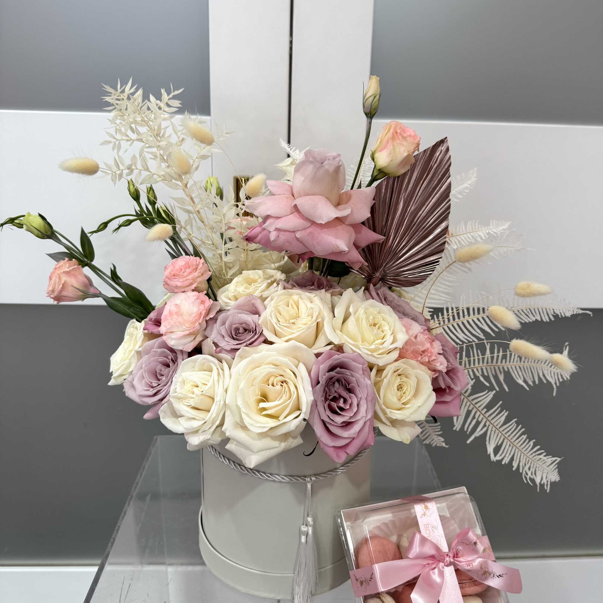 Pink and cream rose arrangement in a round box with a macaron gift box