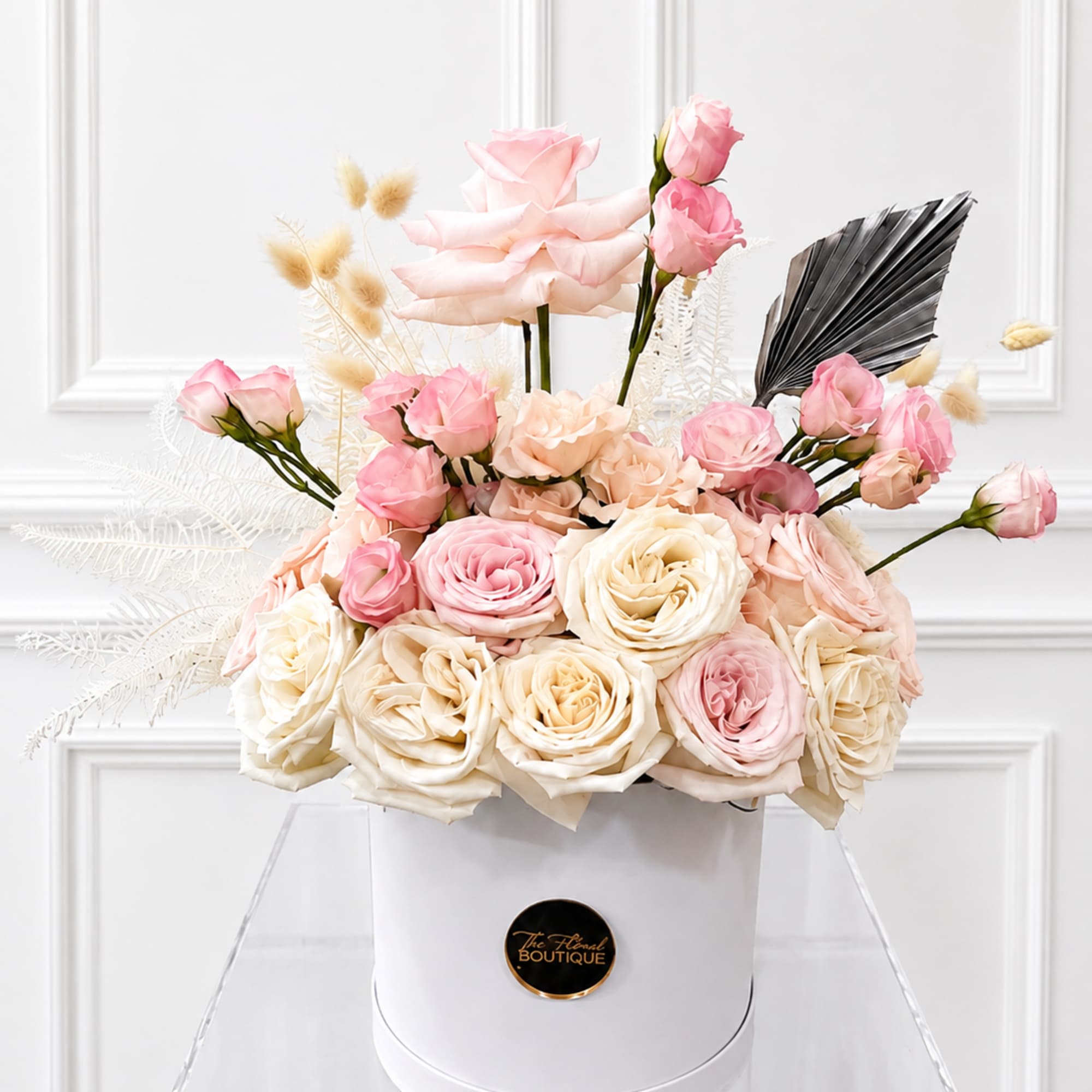 Pink and cream roses arranged in a white hat box