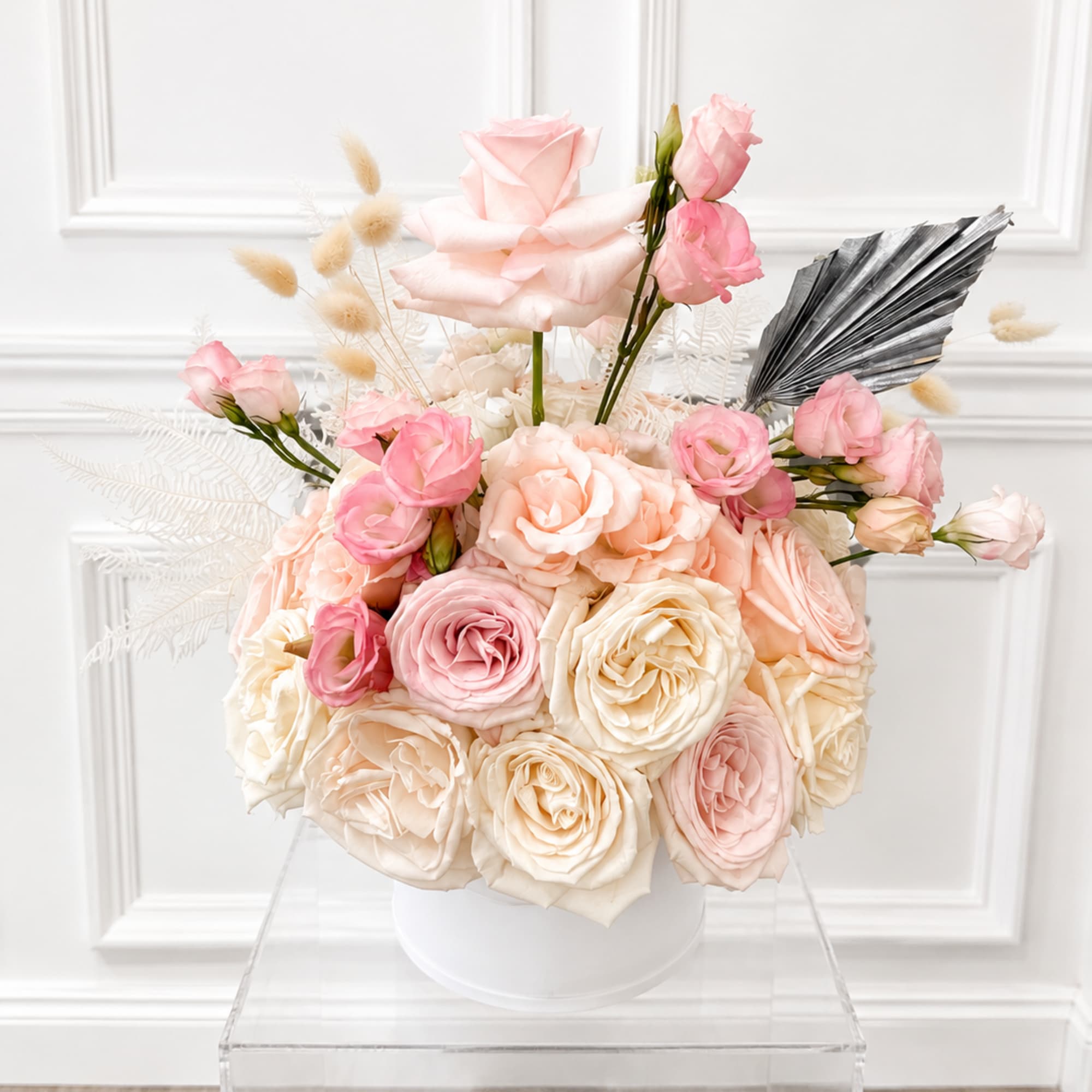 Pink and cream rose arrangement in a white vase