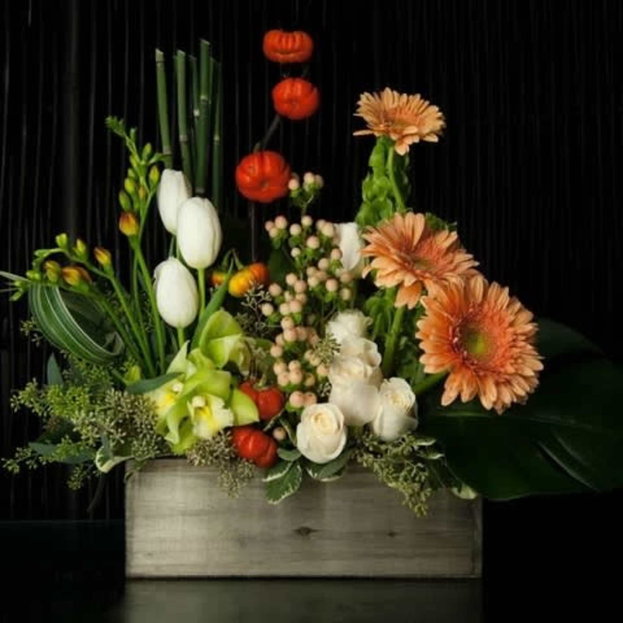 Mixed floral arrangement in a wooden box with orange and white blooms