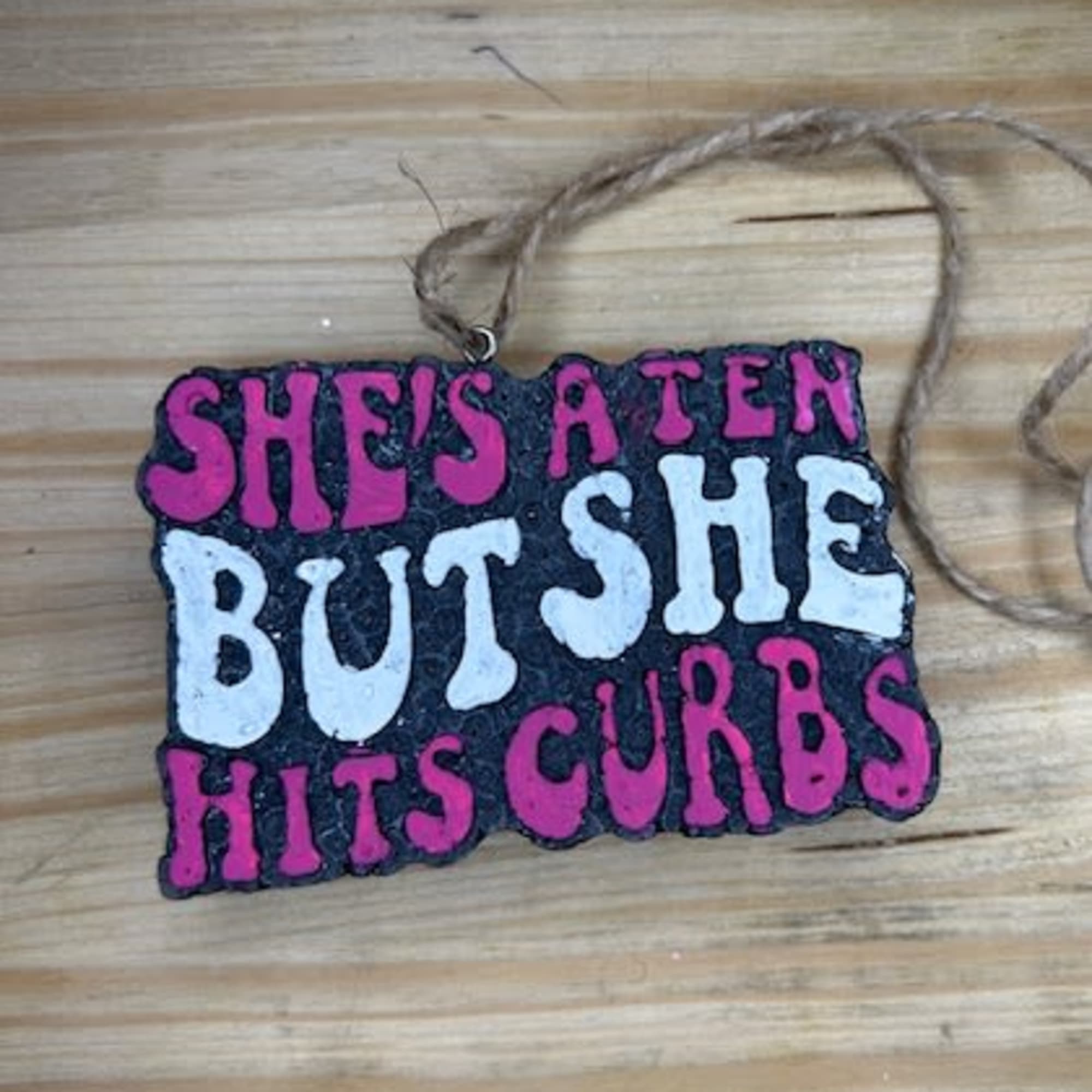 Handmade hanging sign with pink and white text on a black background