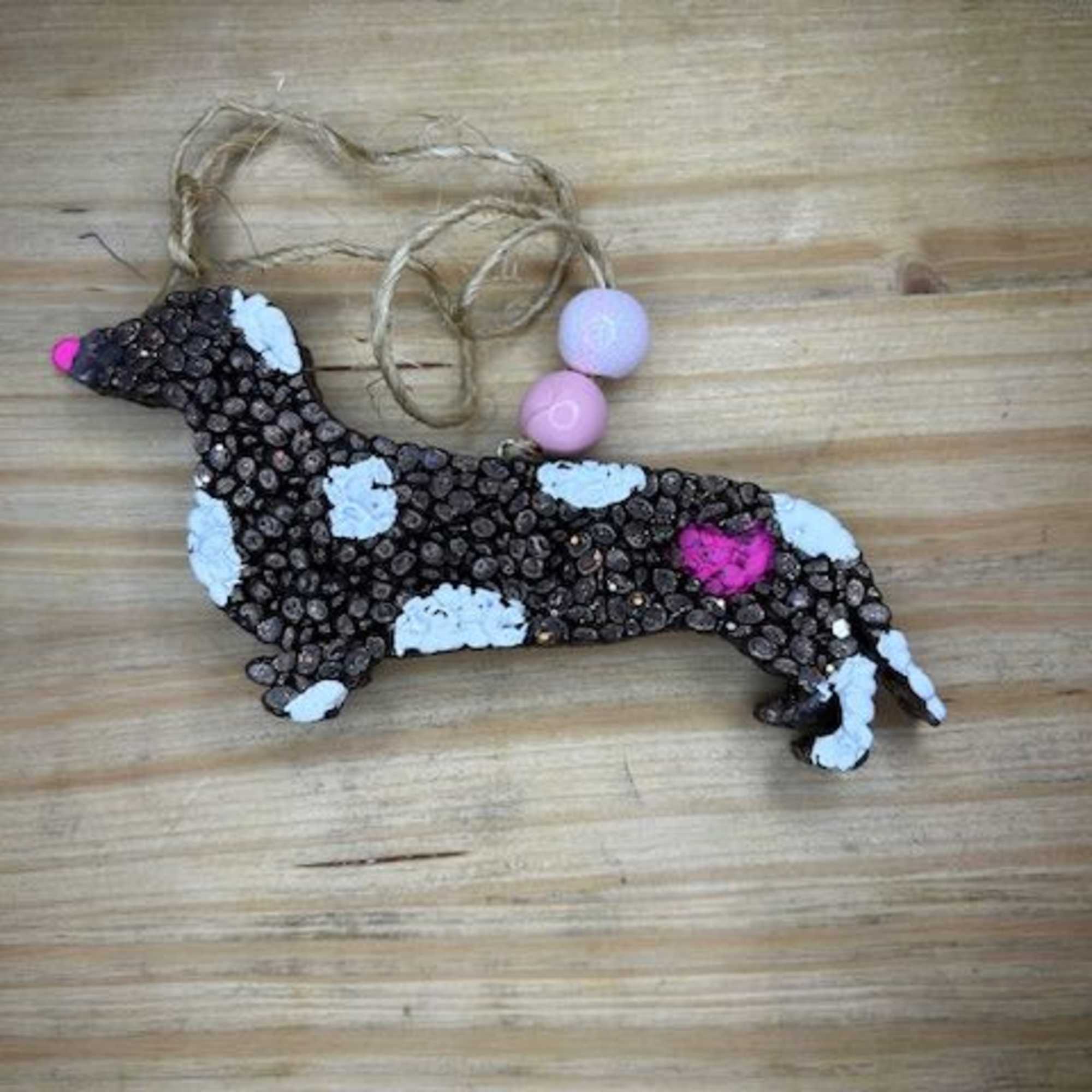 Dog-shaped hanging ornament made of seeds with pink and white accents