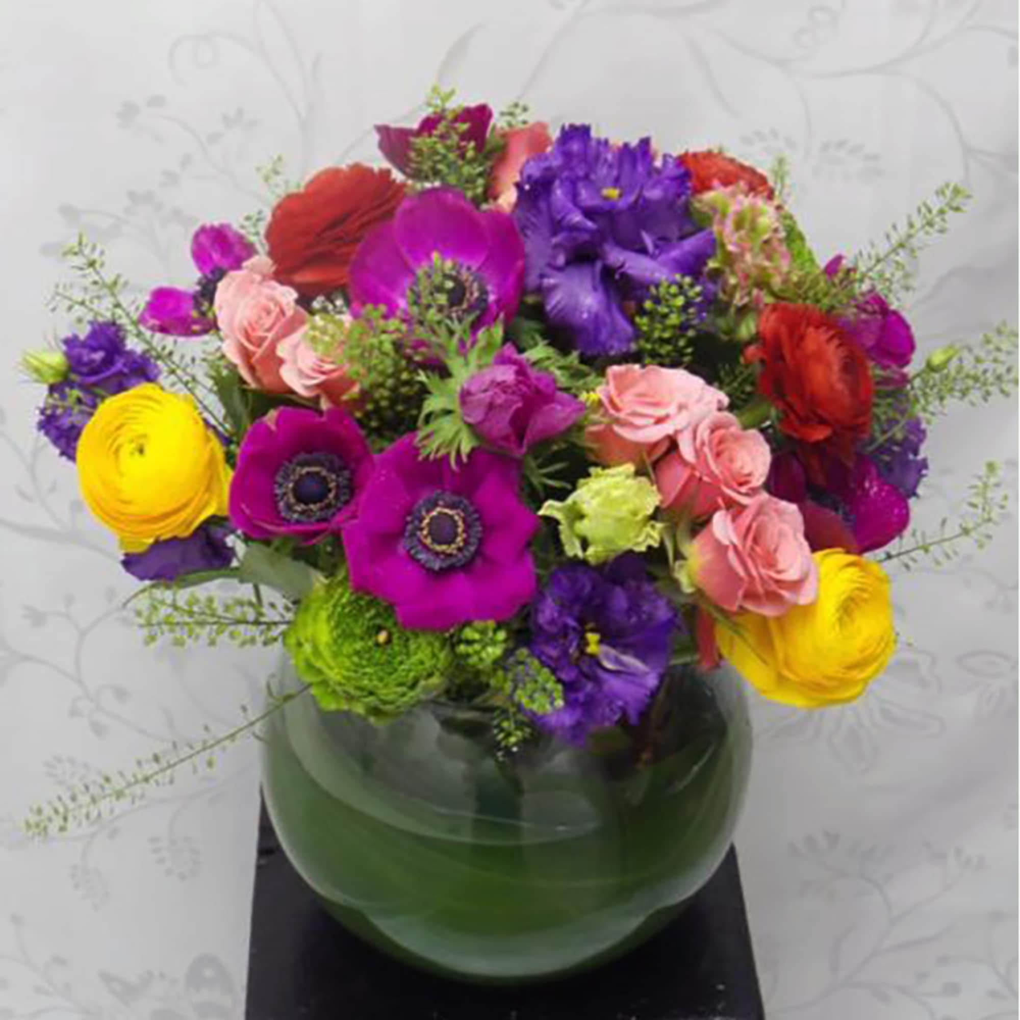 Colorful mixed bouquet in a round green glass vase