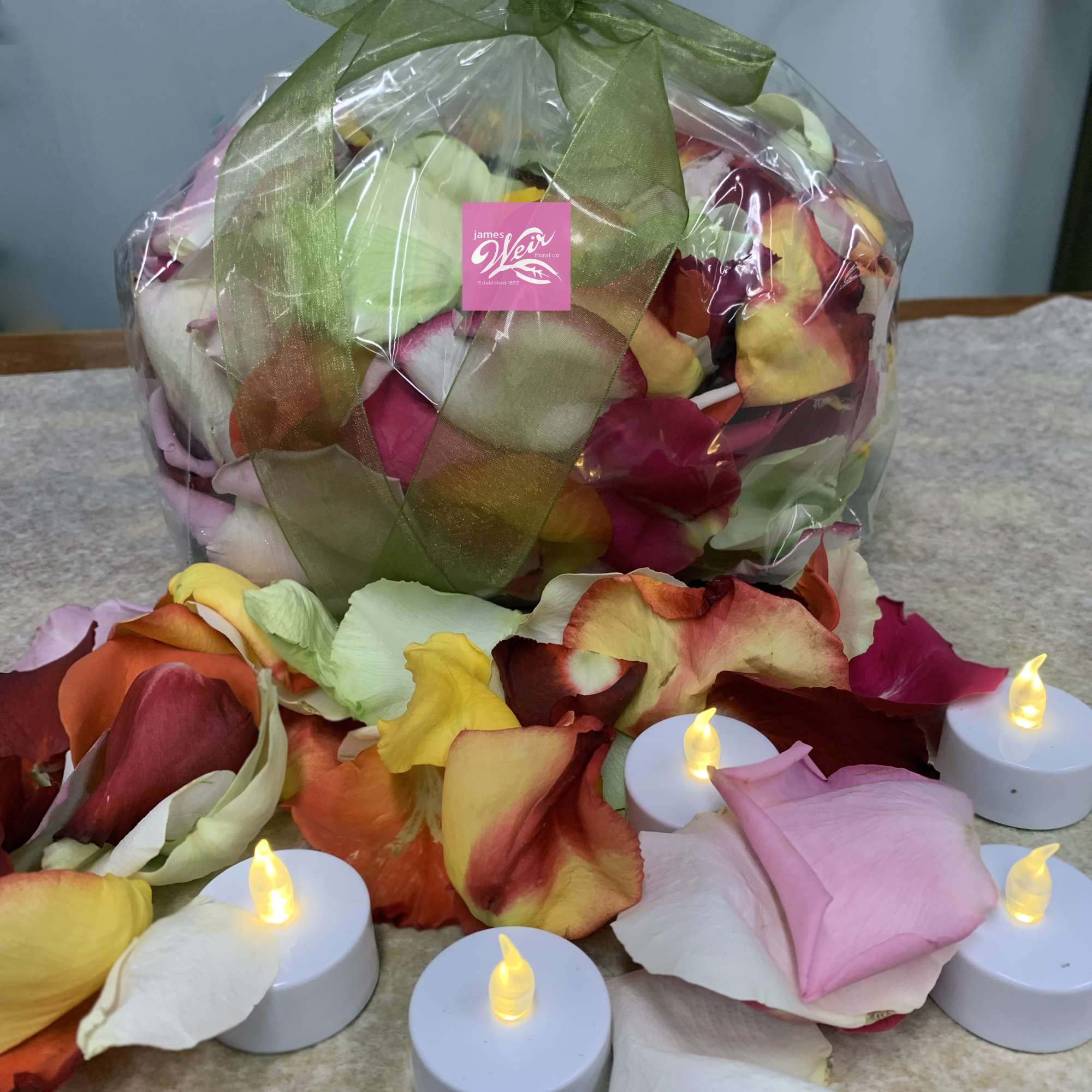 Wrapped bouquet of multicolored rose petals with small LED candles