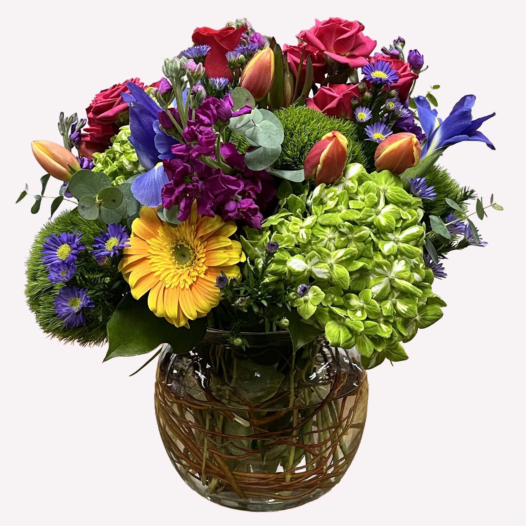 Mixed bouquet of roses, hydrangeas, tulips, and daisies in a glass vase