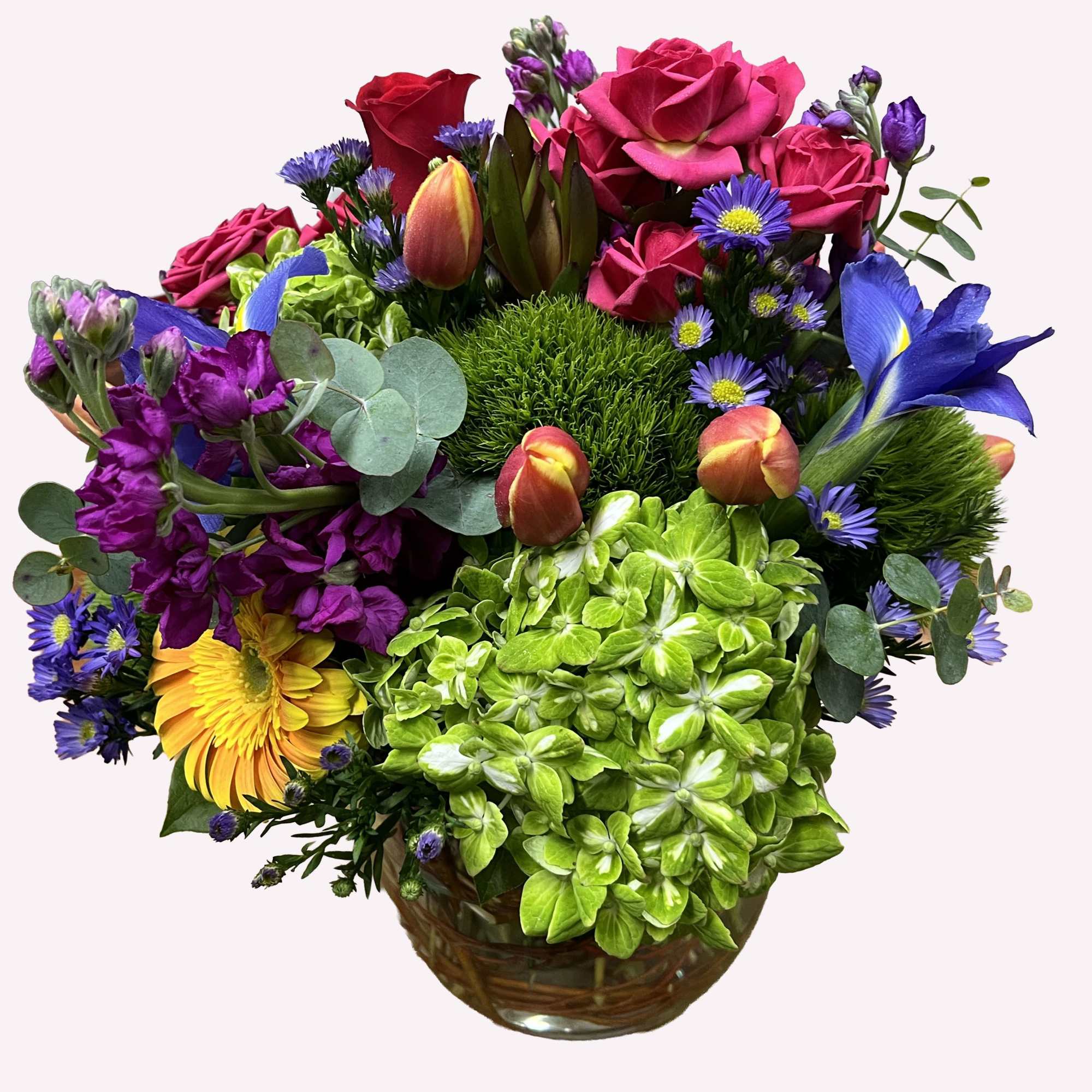 Mixed bouquet with roses, tulips, hydrangea, and daisies in a glass vase