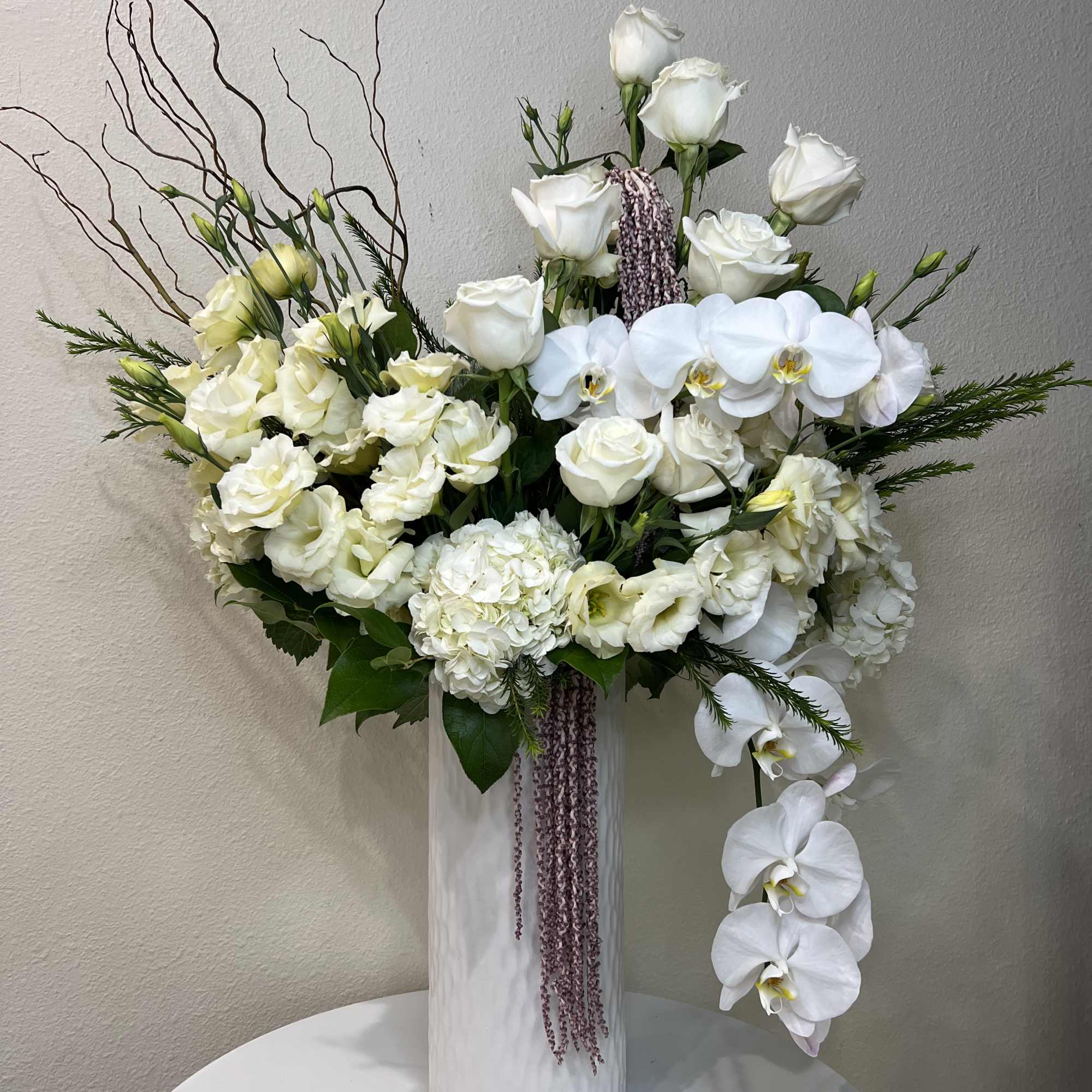 White roses and orchids arranged in a tall white vase, photo 2 of 2