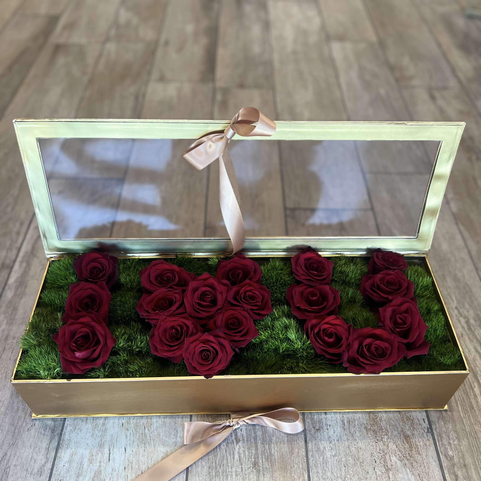 Rectangular box of deep red roses with a clear lid and ribbon