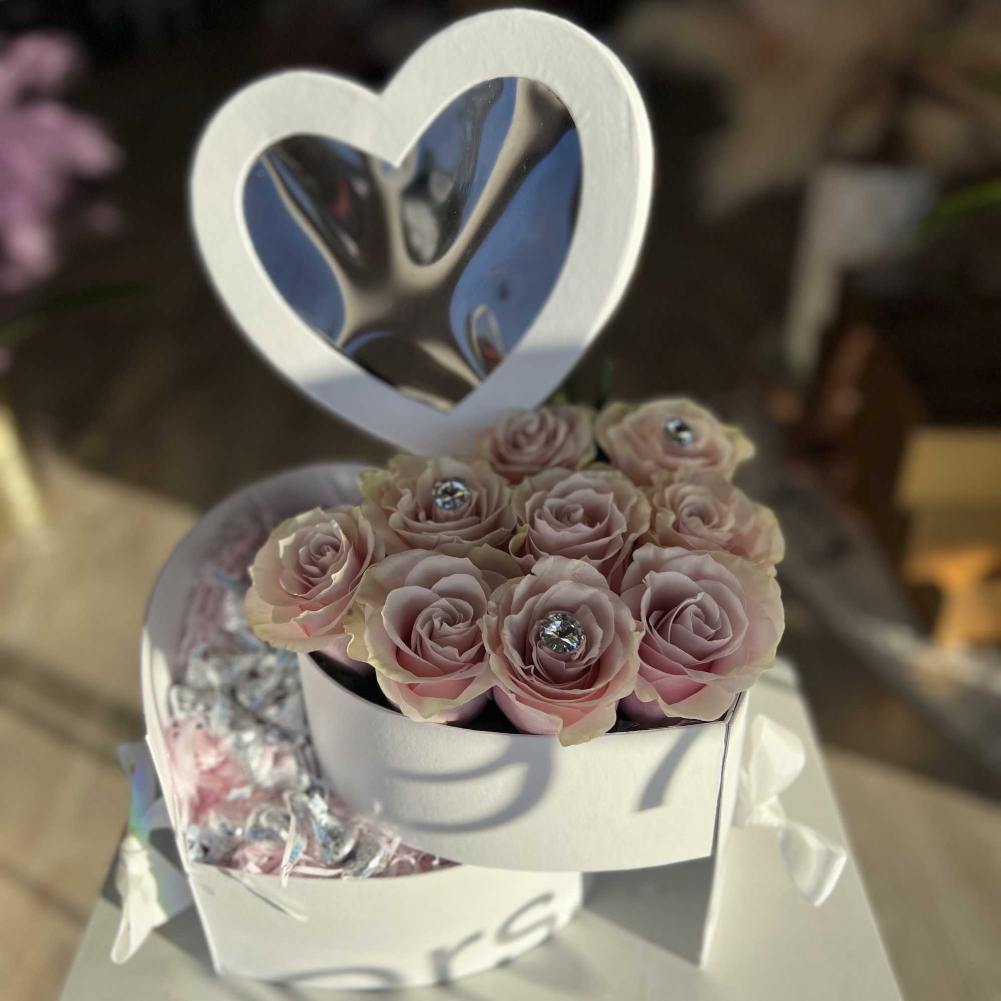 Pink roses in a white heart-shaped gift box with a heart topper