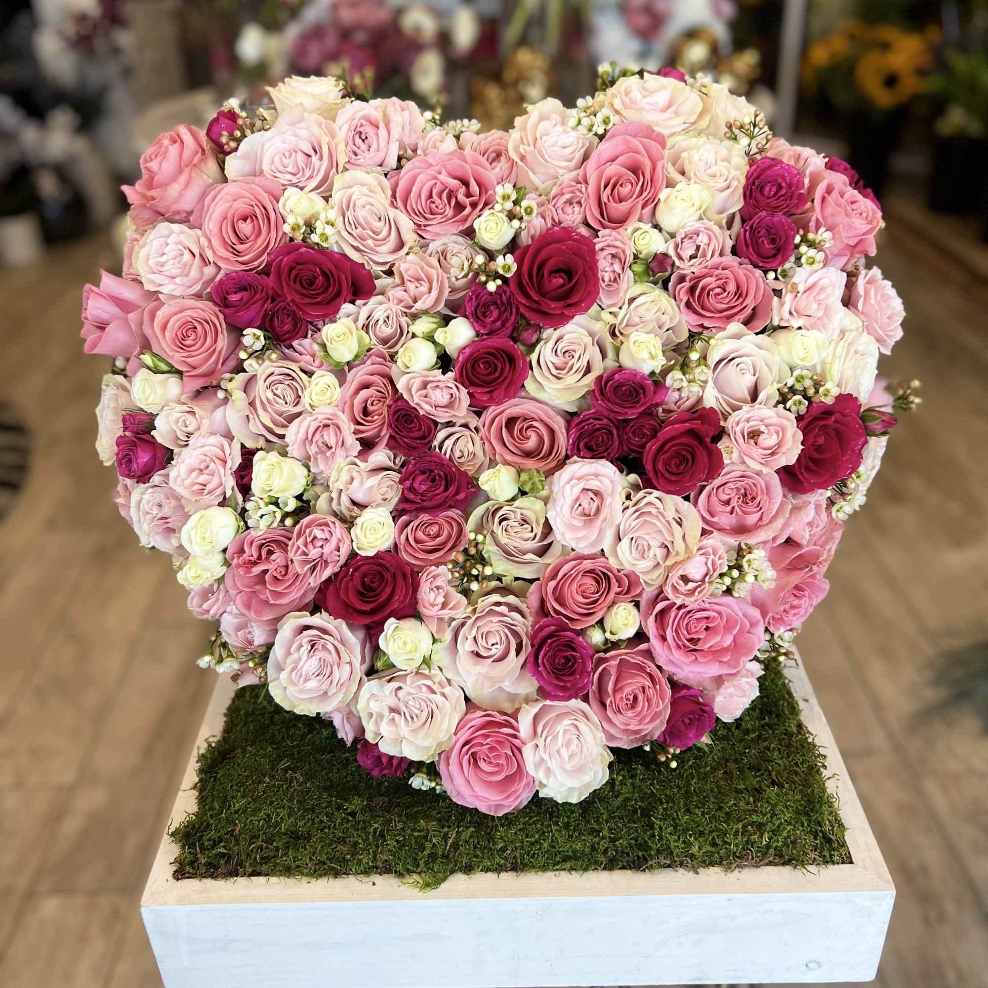 Heart-shaped arrangement of pink and white roses on a moss-covered base, photo 2 of 2