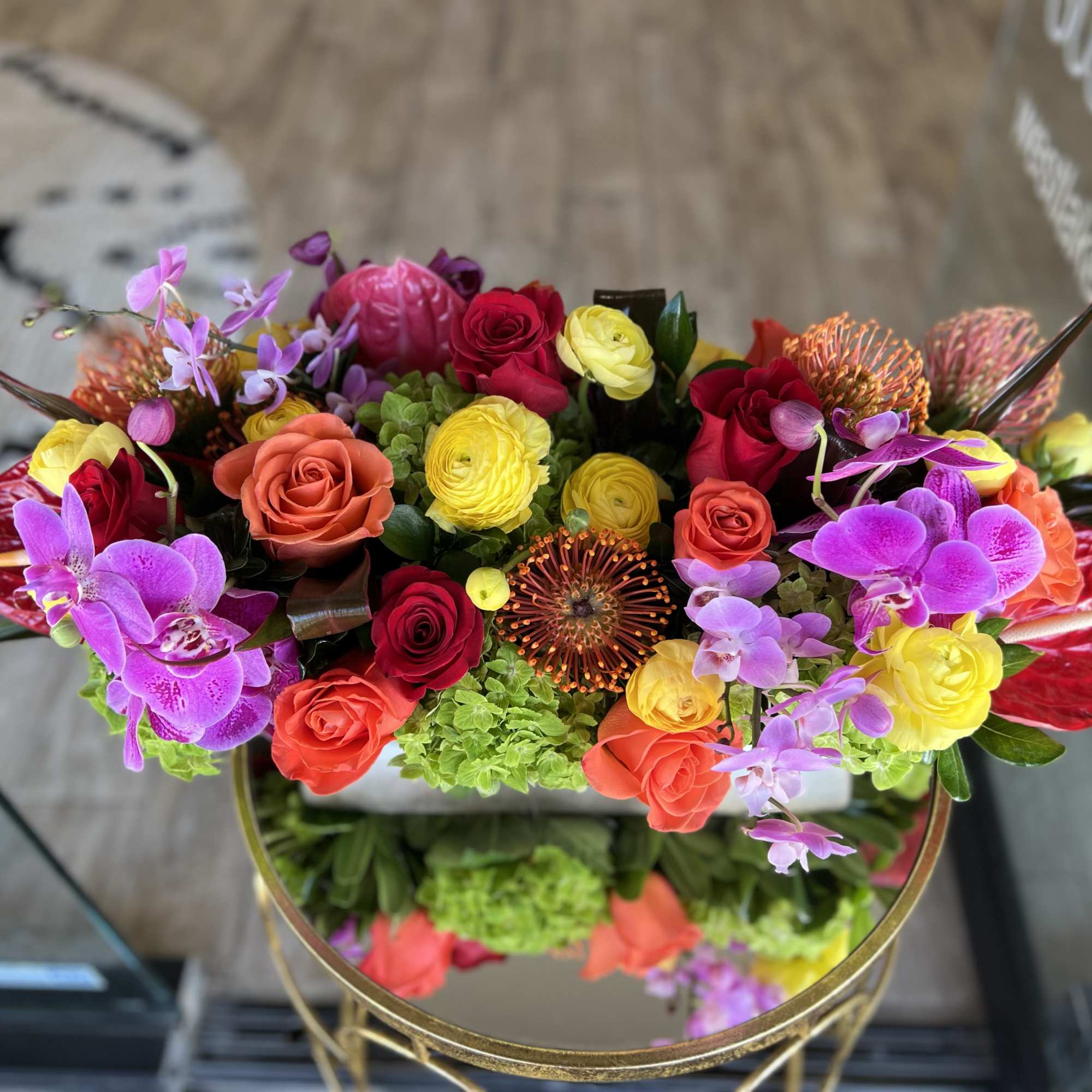 Colorful bouquet of roses and orchids in a round gold vase