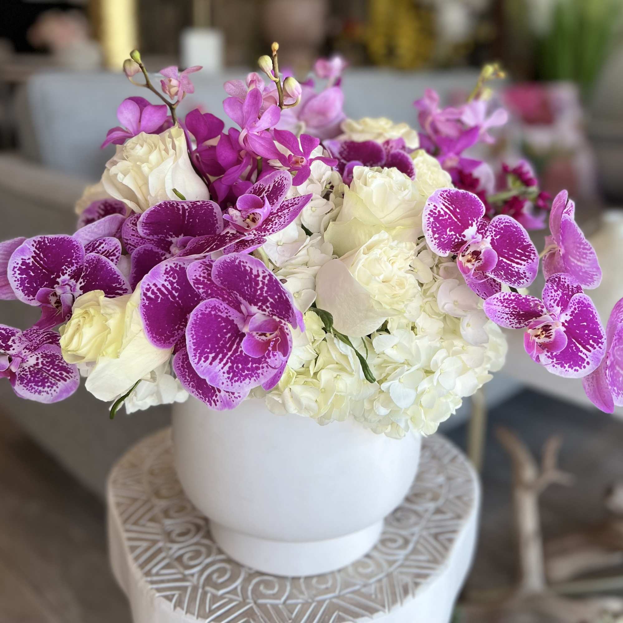 White and magenta orchid arrangement in a white vase