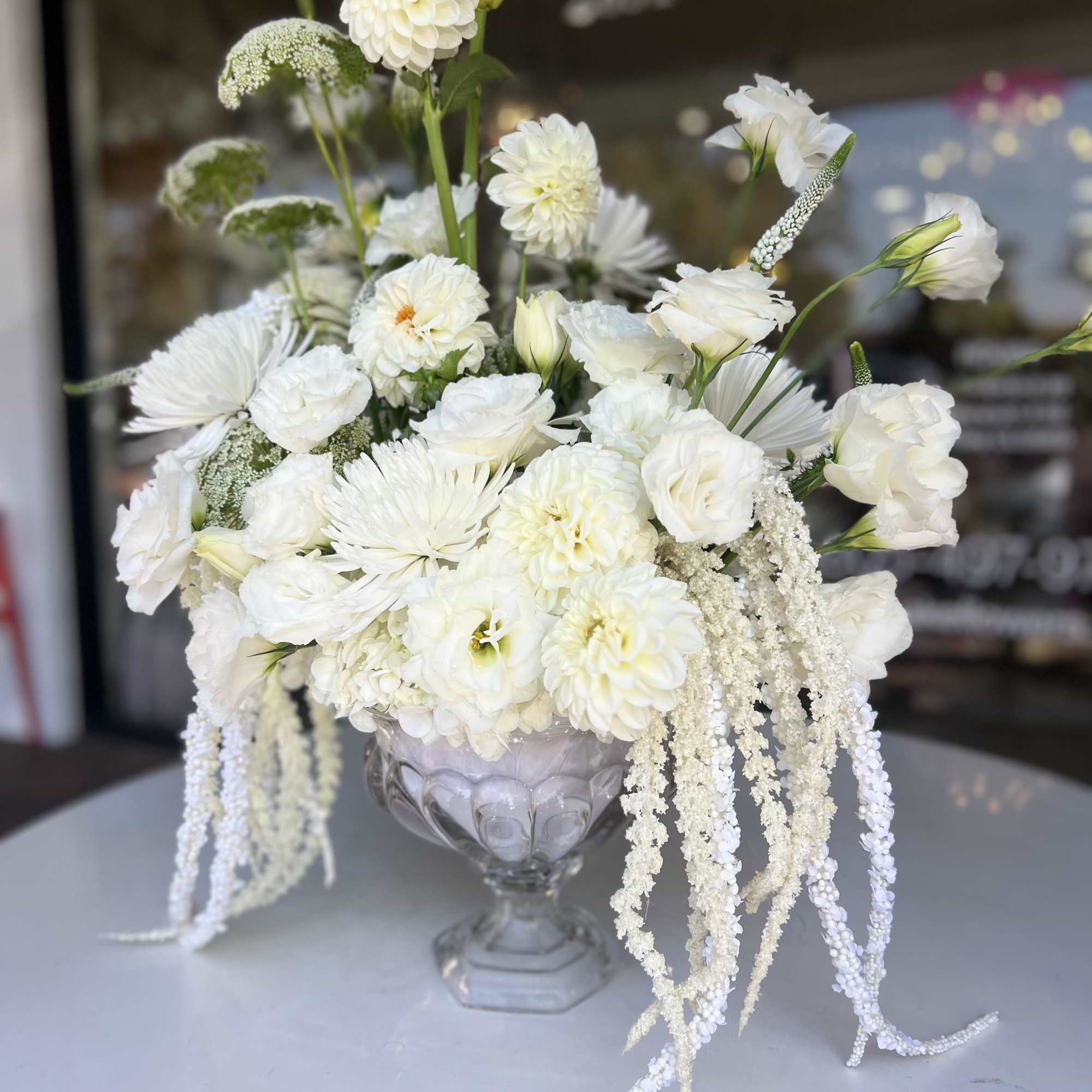 White floral arrangement in a clear glass pedestal vase