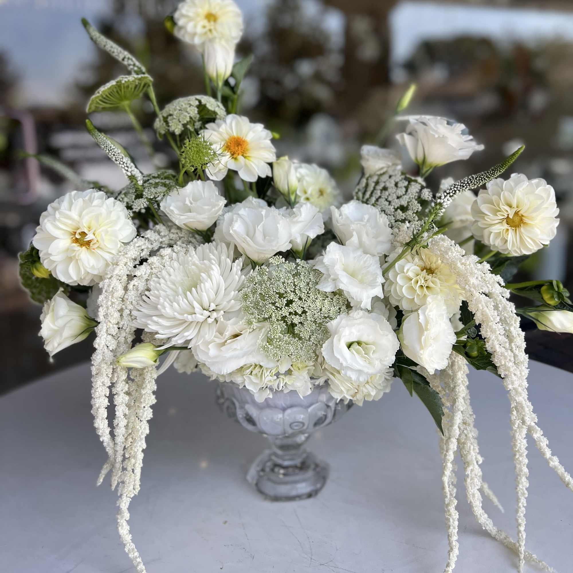 White floral arrangement in a clear glass vase with cascading blooms