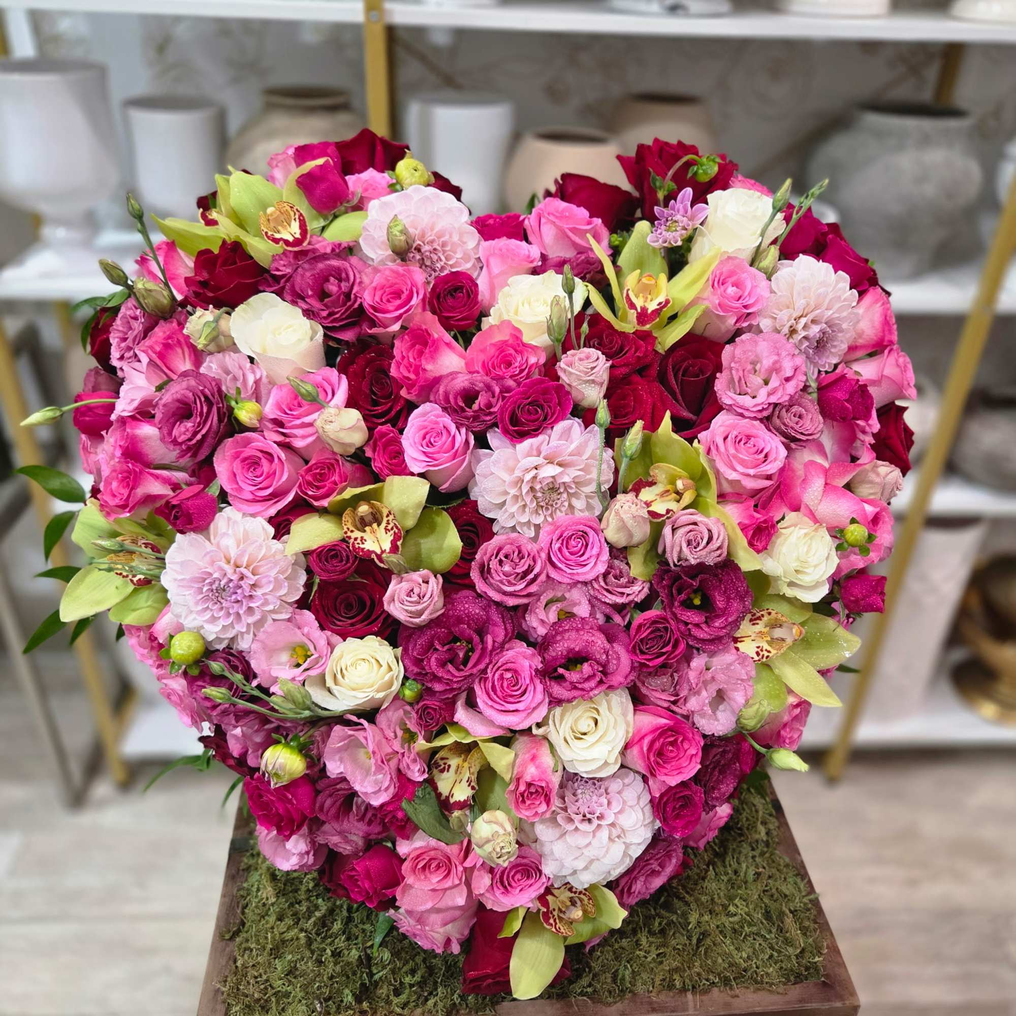 Heart-shaped bouquet of pink and red roses with orchids and dahlias