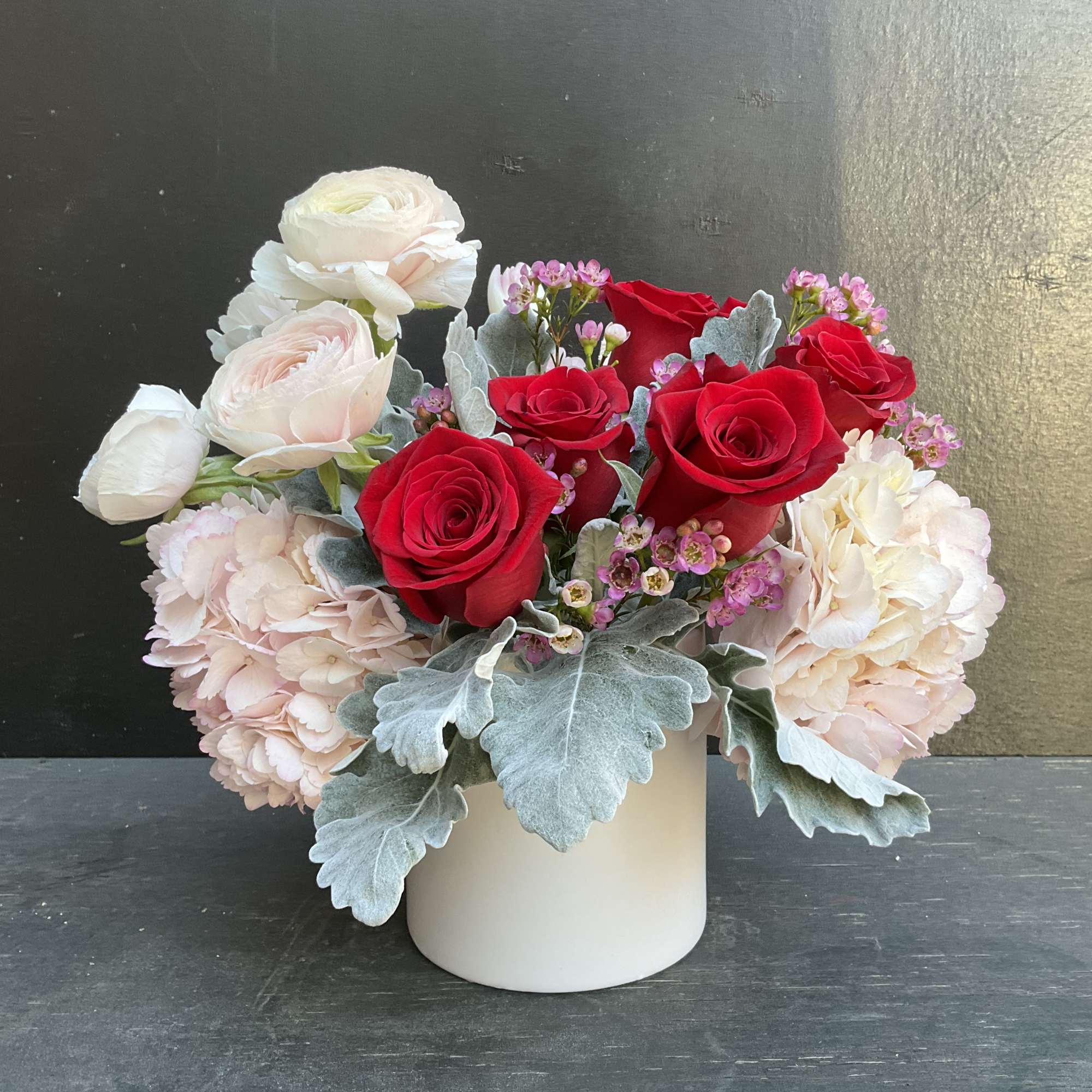 Red and white roses with pale pink blooms in a white vase