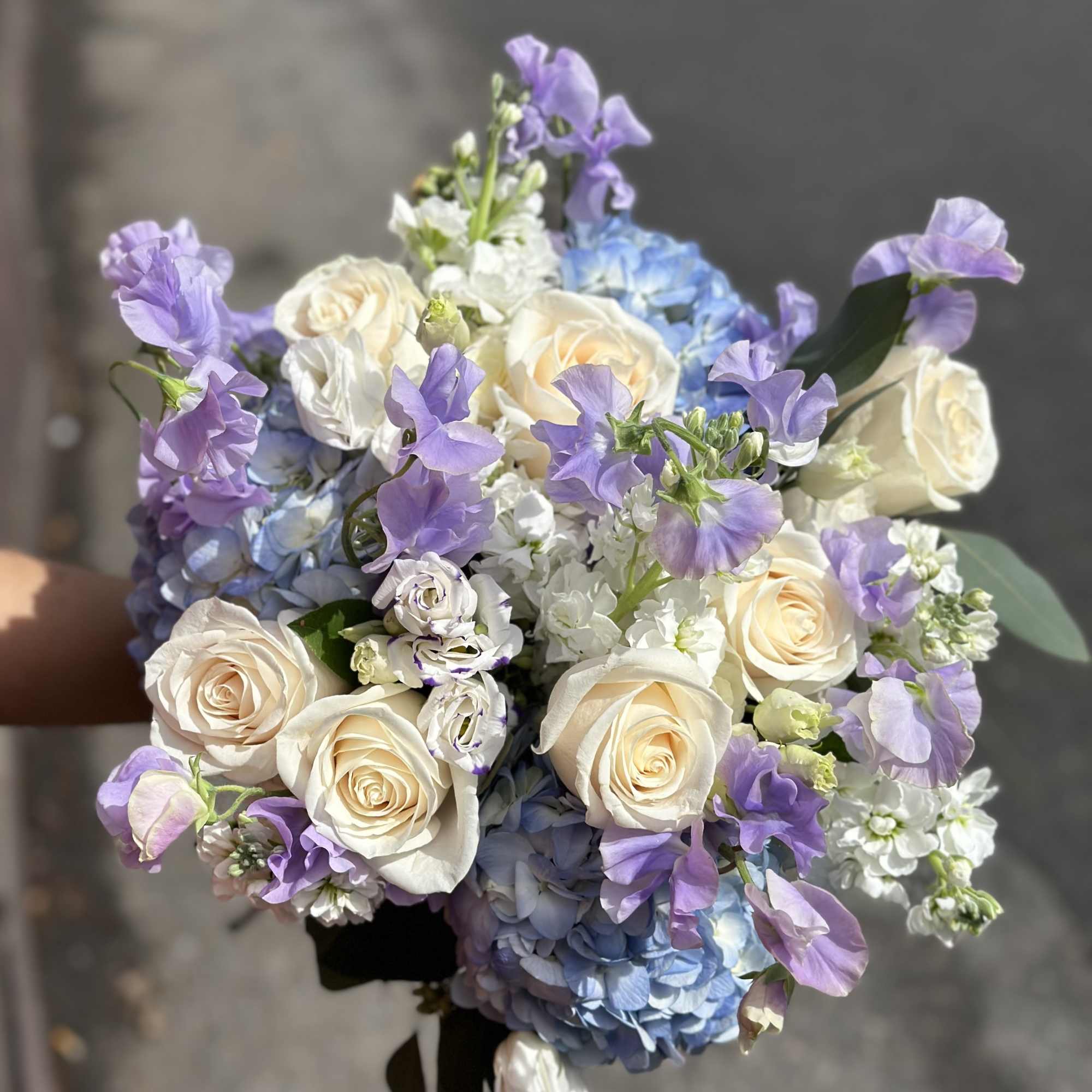 Bouquet of cream roses, blue hydrangeas, and lavender flowers