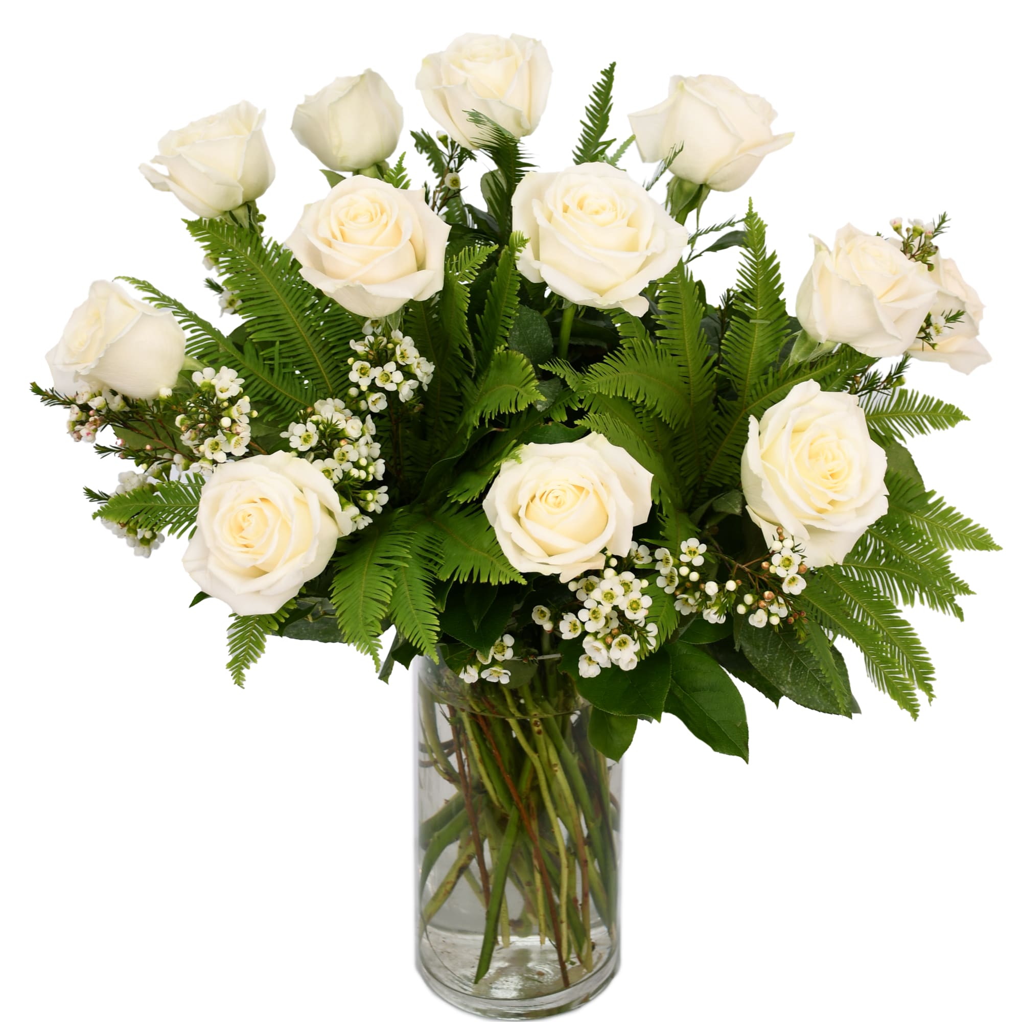 White roses arranged in a clear glass vase with fern greenery
