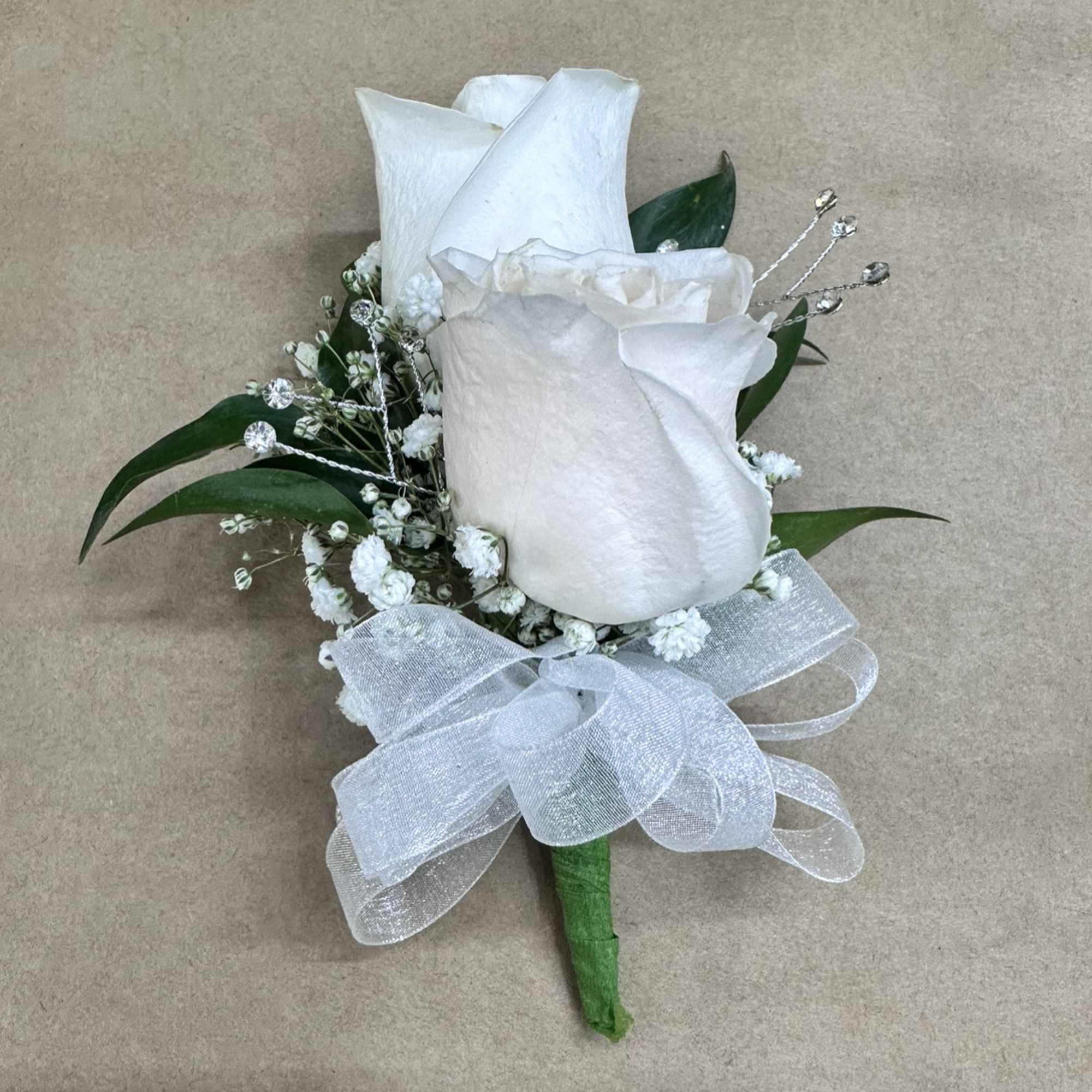 White rose boutonniere with baby's breath, crystal accents, and a sheer white bow.