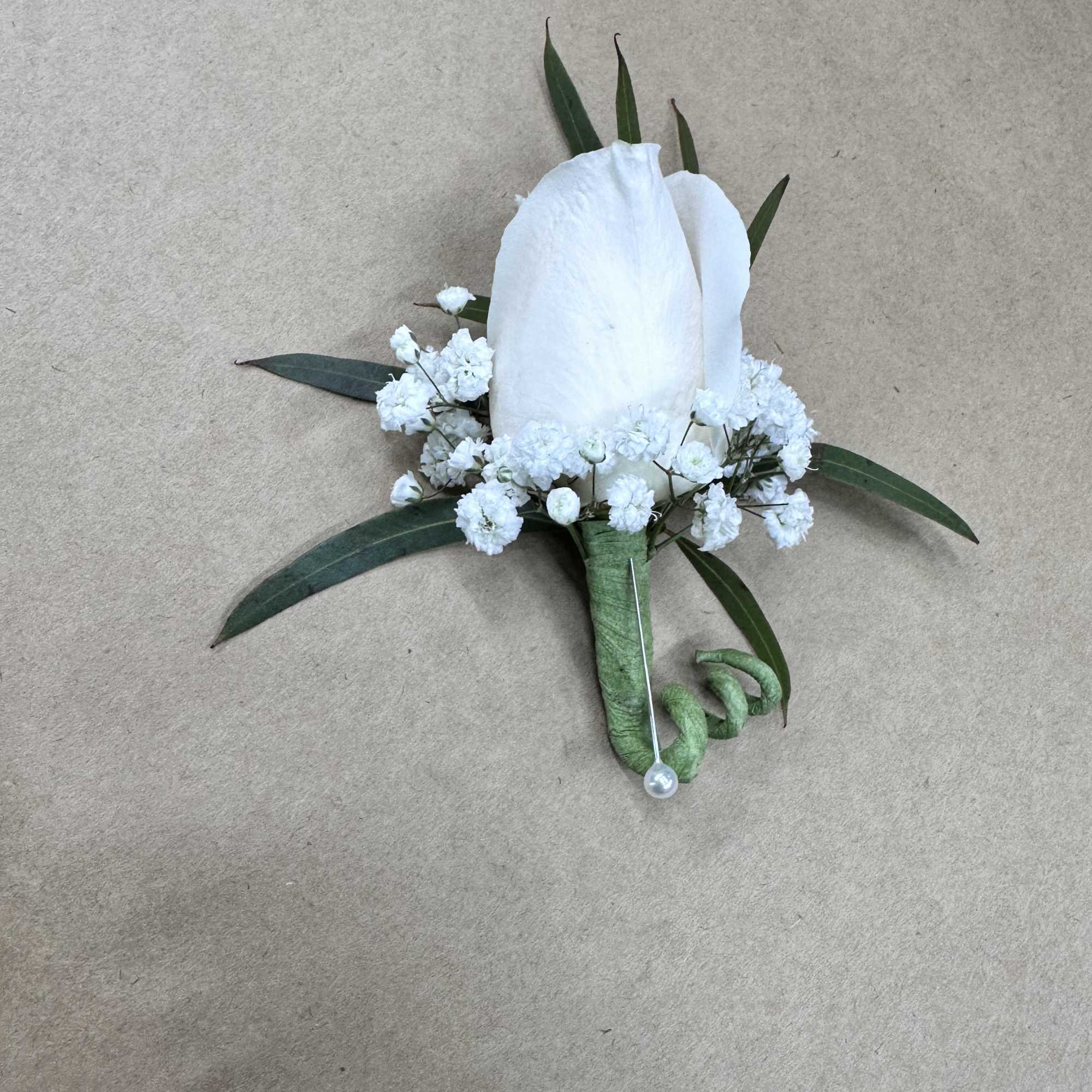 White boutonniere with small white flowers and green leaves