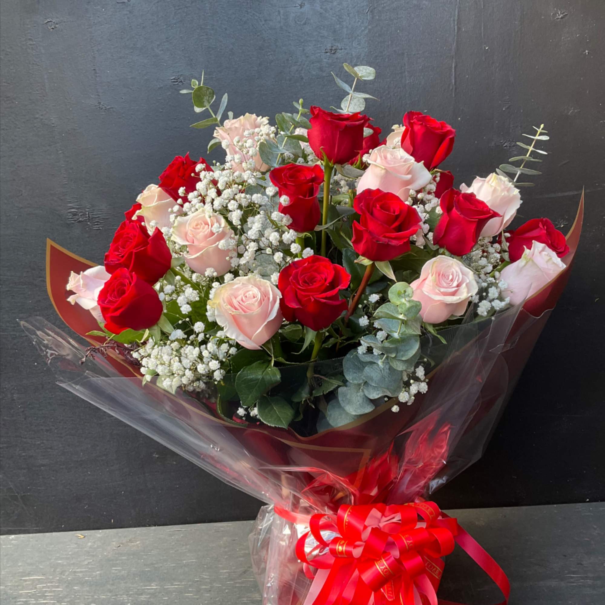 Bouquet of red and pale pink roses with baby's breath in clear wrap
