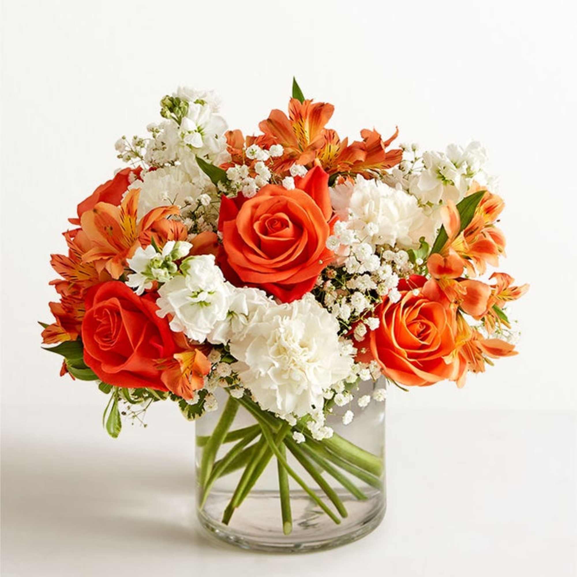 Orange roses and white carnations in a clear glass vase