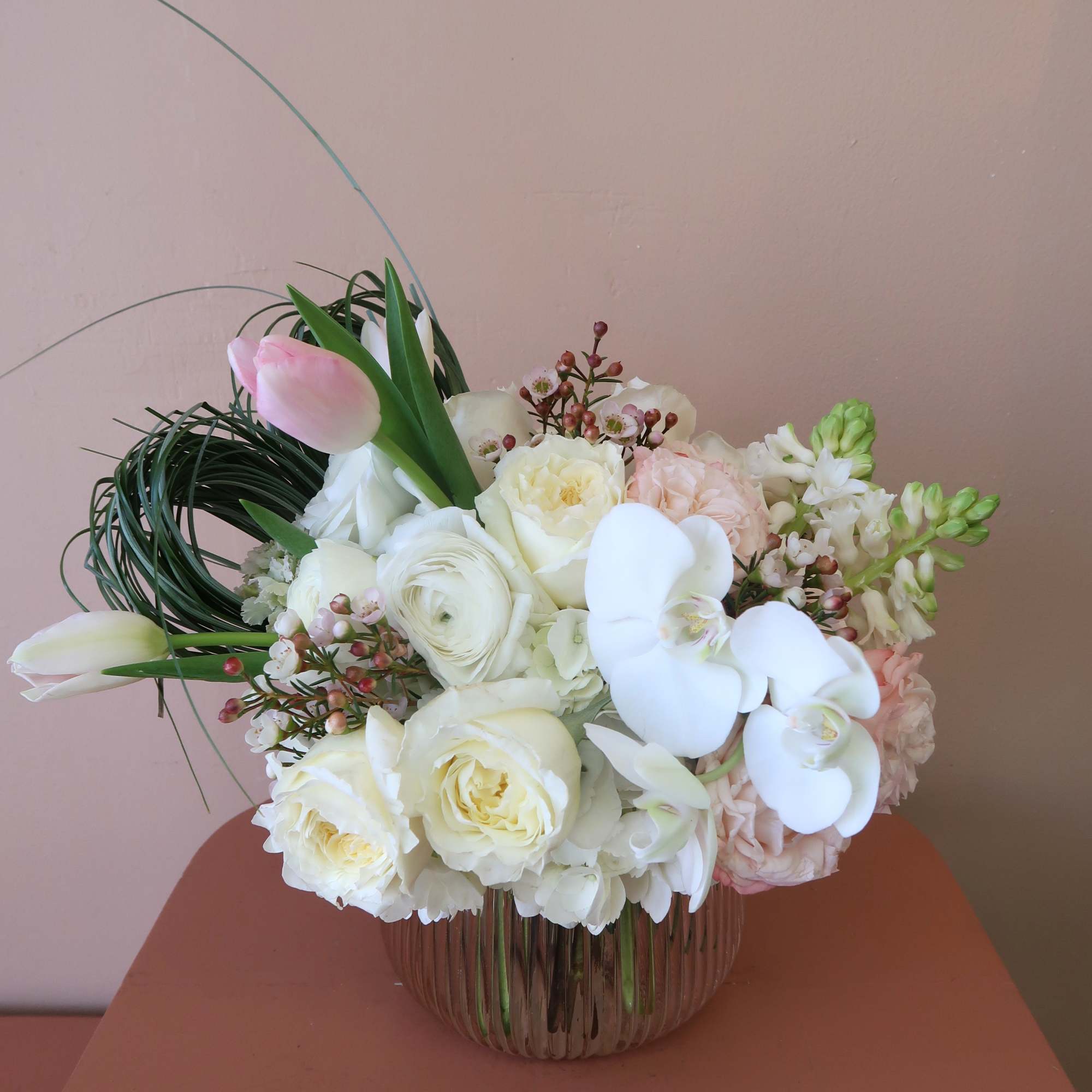 White and blush bouquet with orchids and roses in a glass vase