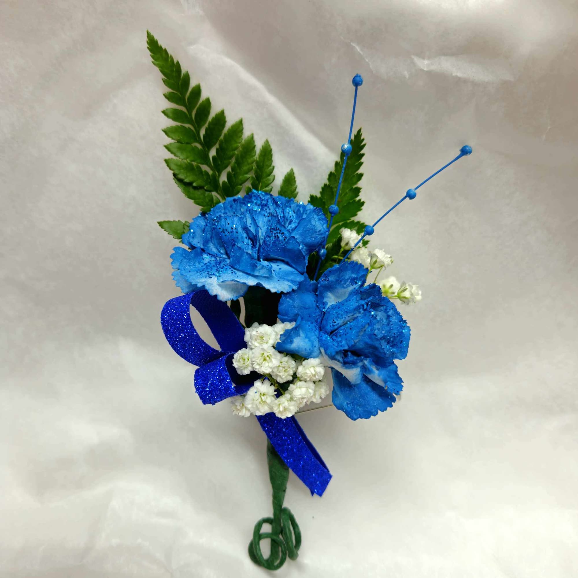 Blue carnation boutonniere with white filler and a glitter ribbon