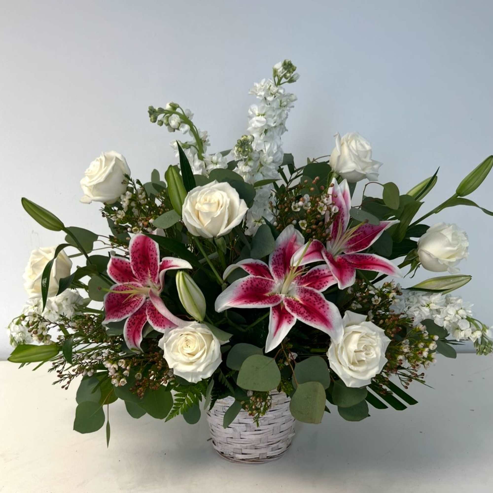 White roses and pink lilies in a white basket vase