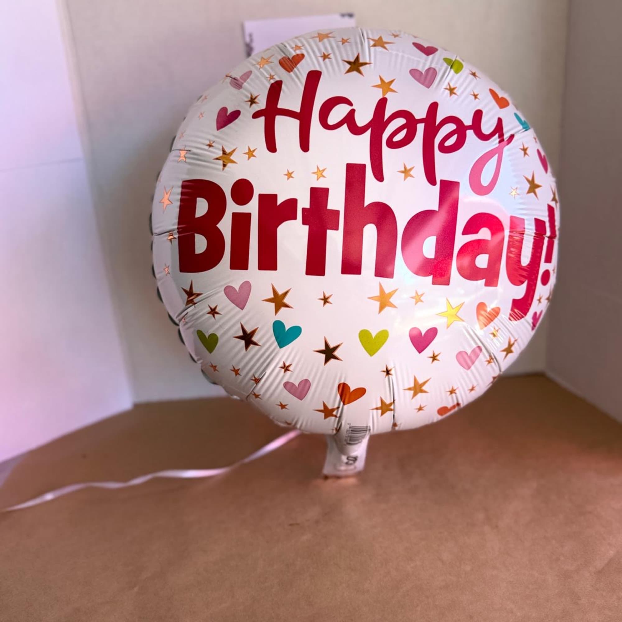 Round birthday balloon with colorful hearts and stars