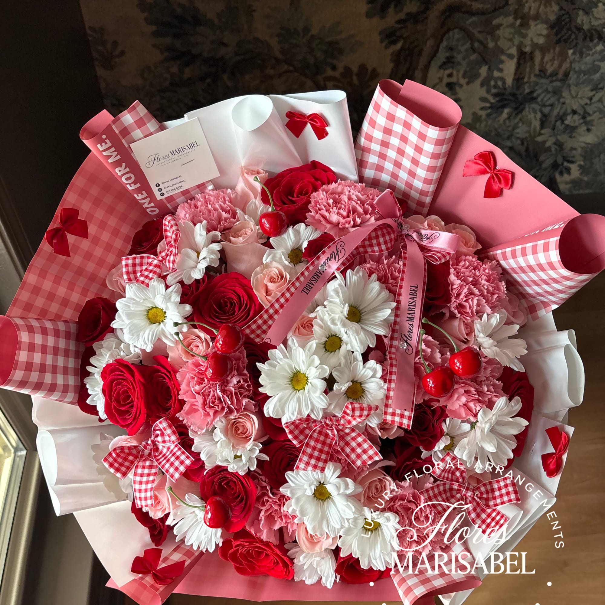 Bouquet of red and pink roses with white daisies and carnations in pink wrapping