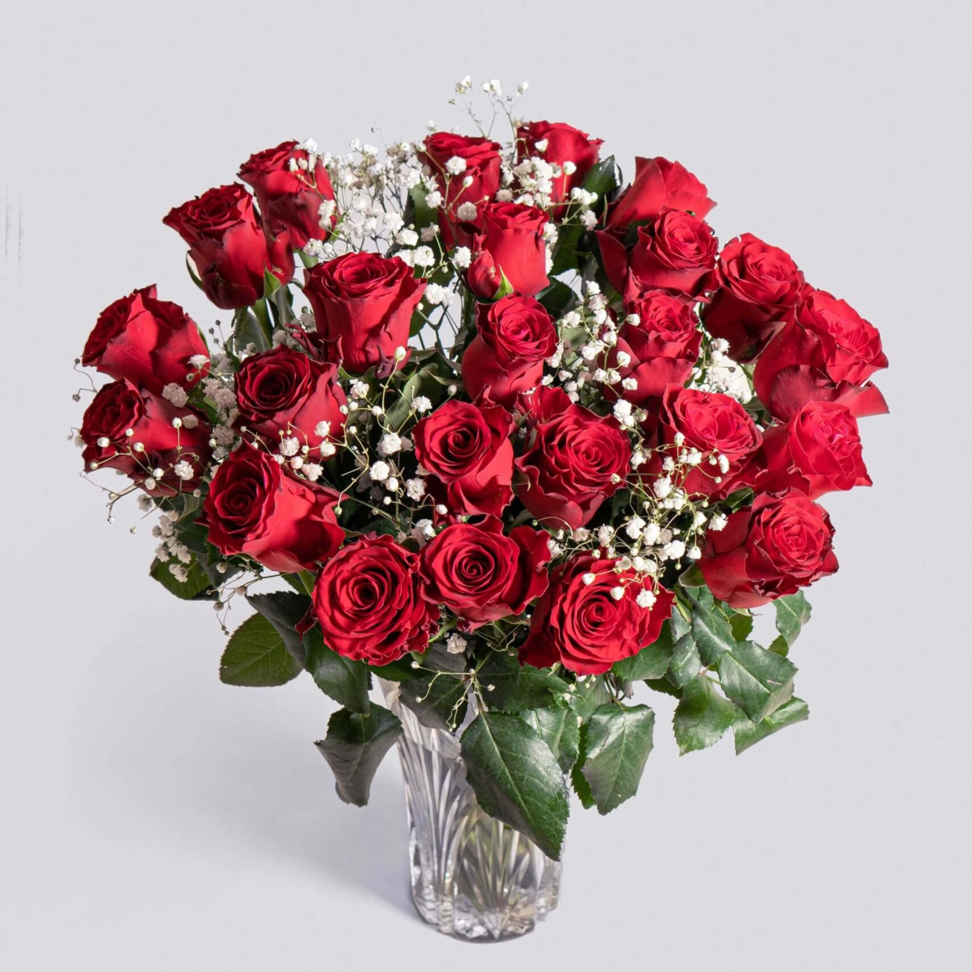 Bouquet of red roses with white baby's breath in a clear glass vase