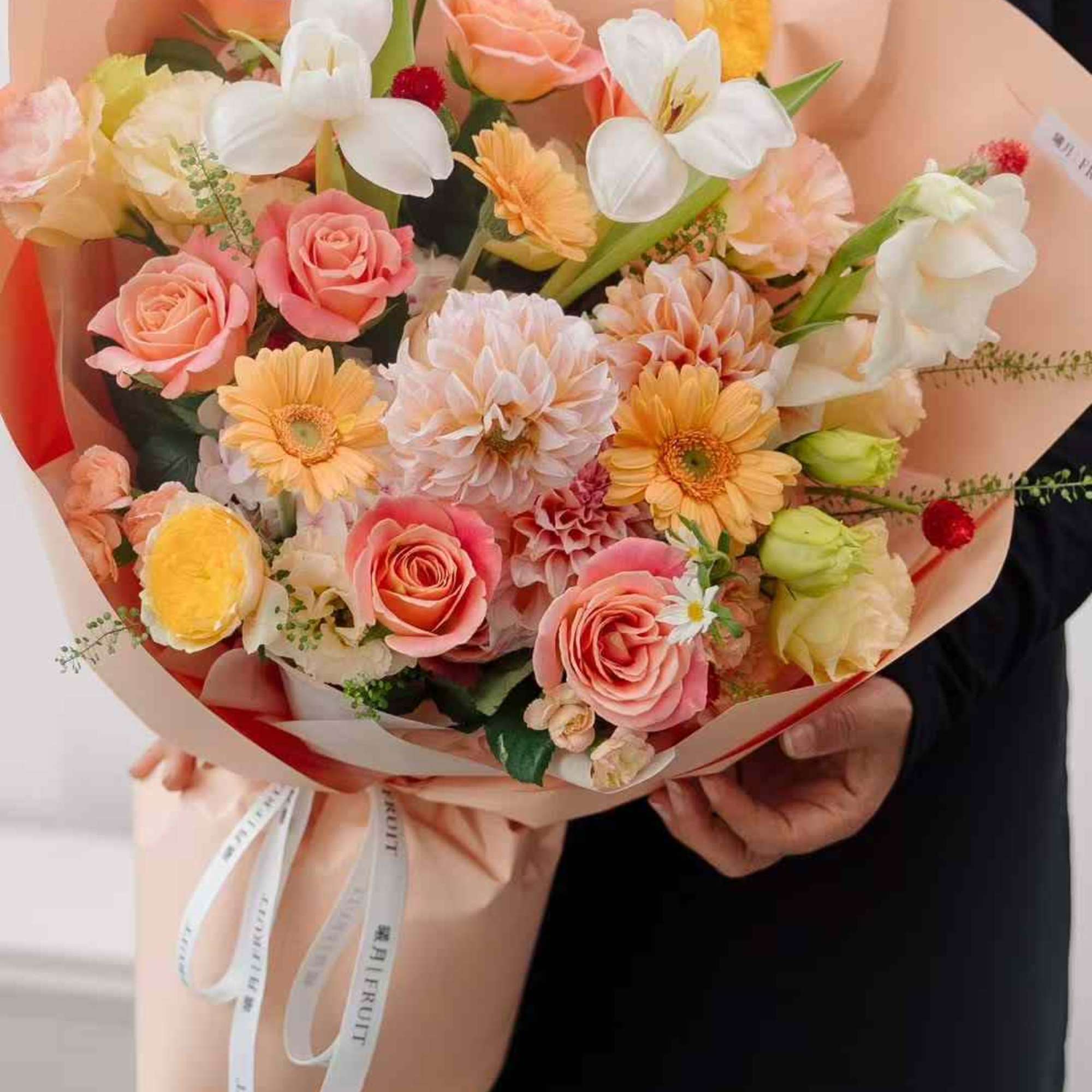 Bouquet of pink and peach flowers with white blooms wrapped in blush paper