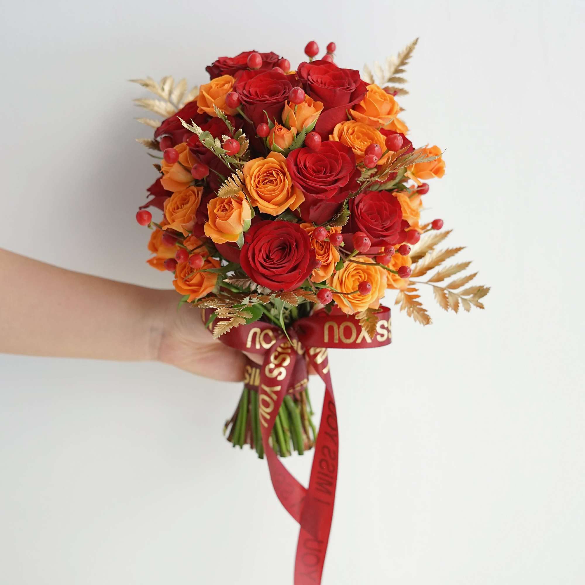 Handheld bouquet of red and orange roses with a red ribbon, photo 3 of 4