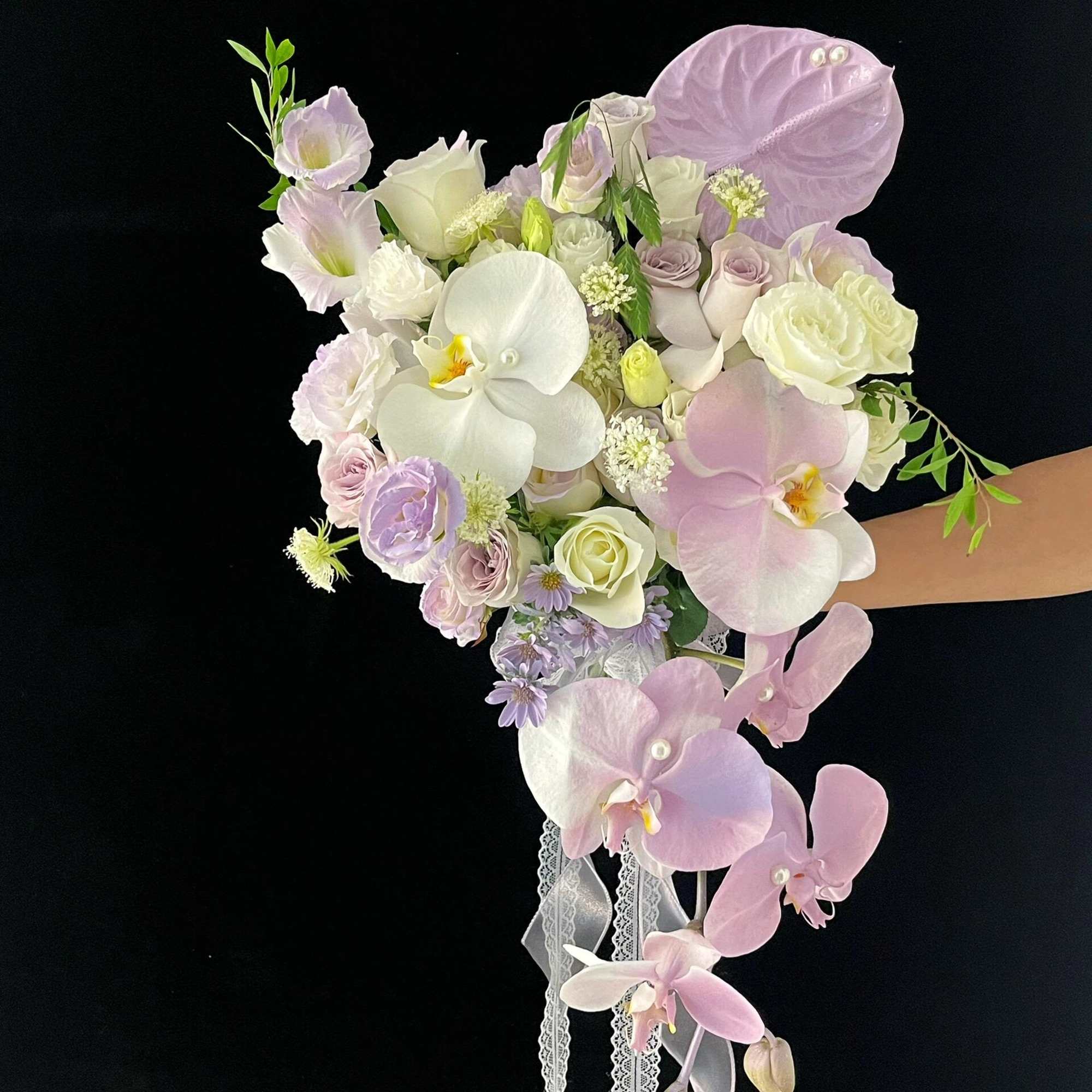 Pastel bouquet with orchids, roses, and lace ribbon