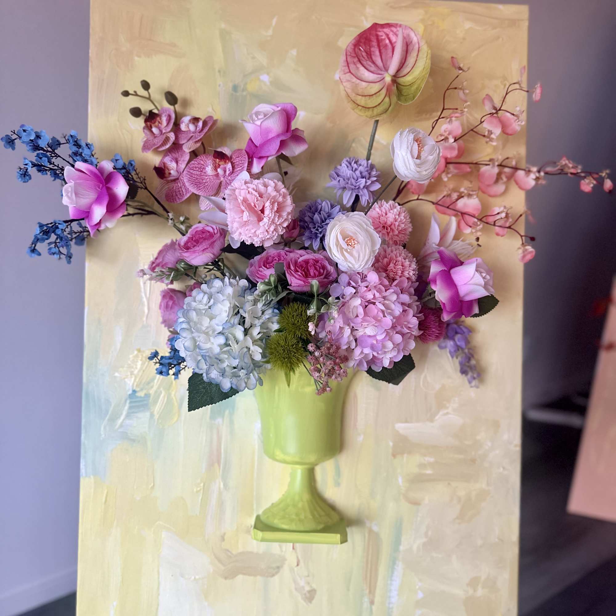 Floral arrangement in a green vase with pink, purple, and blue blooms