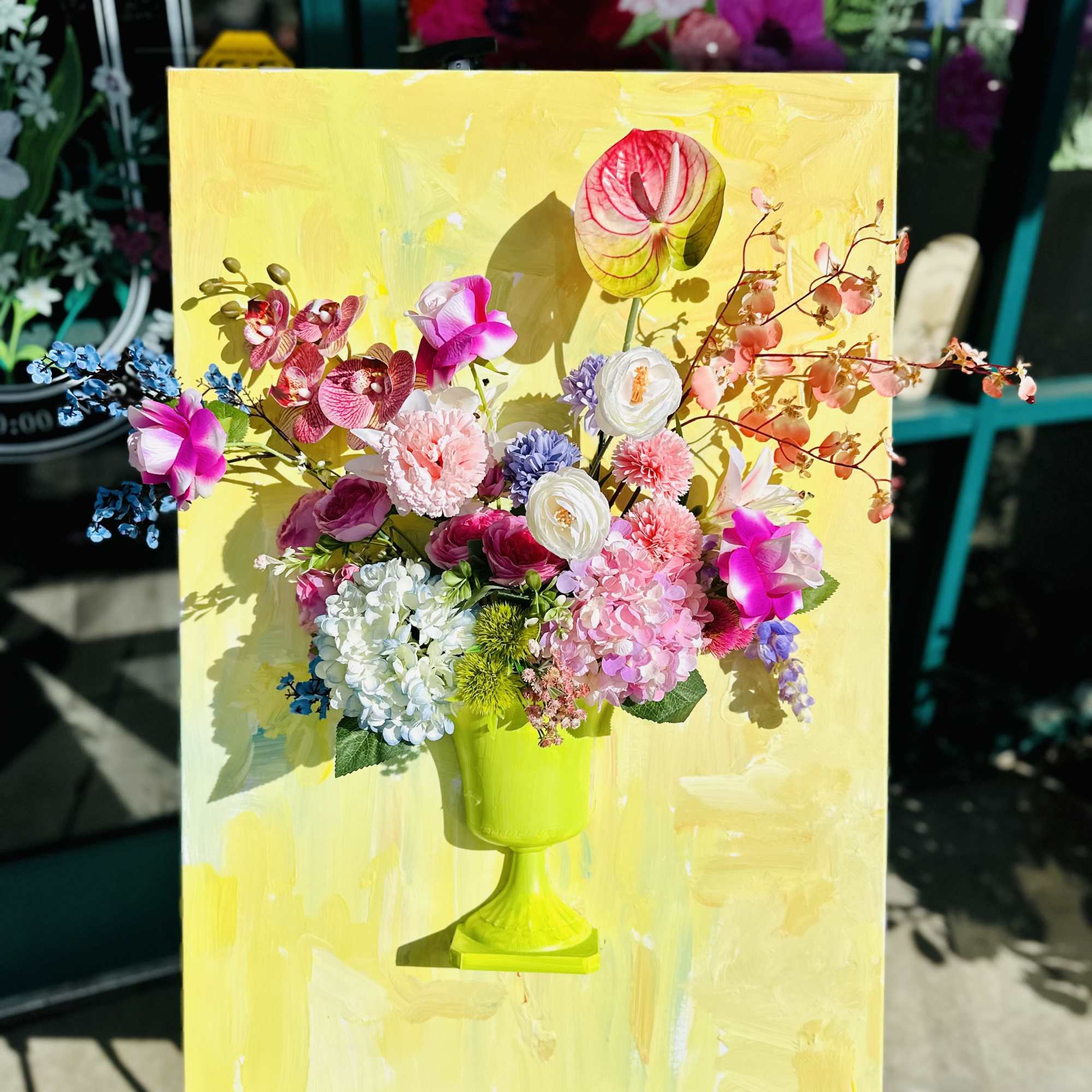 Colorful floral arrangement in a lime green vase on a yellow canvas