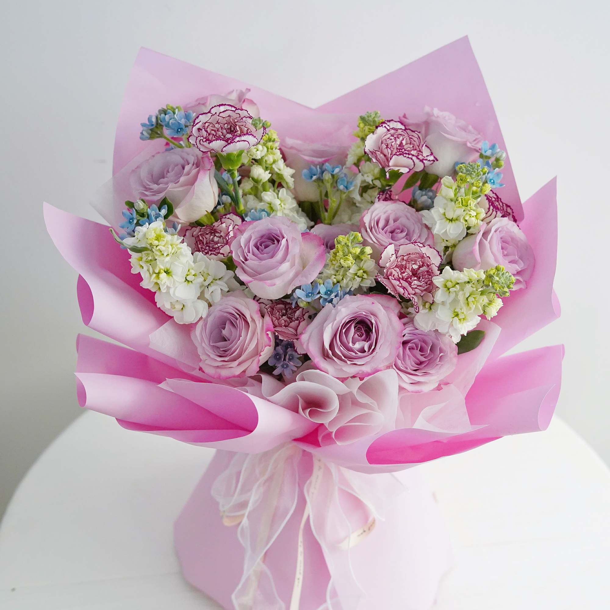 Pink bouquet of roses and carnations wrapped in pink paper