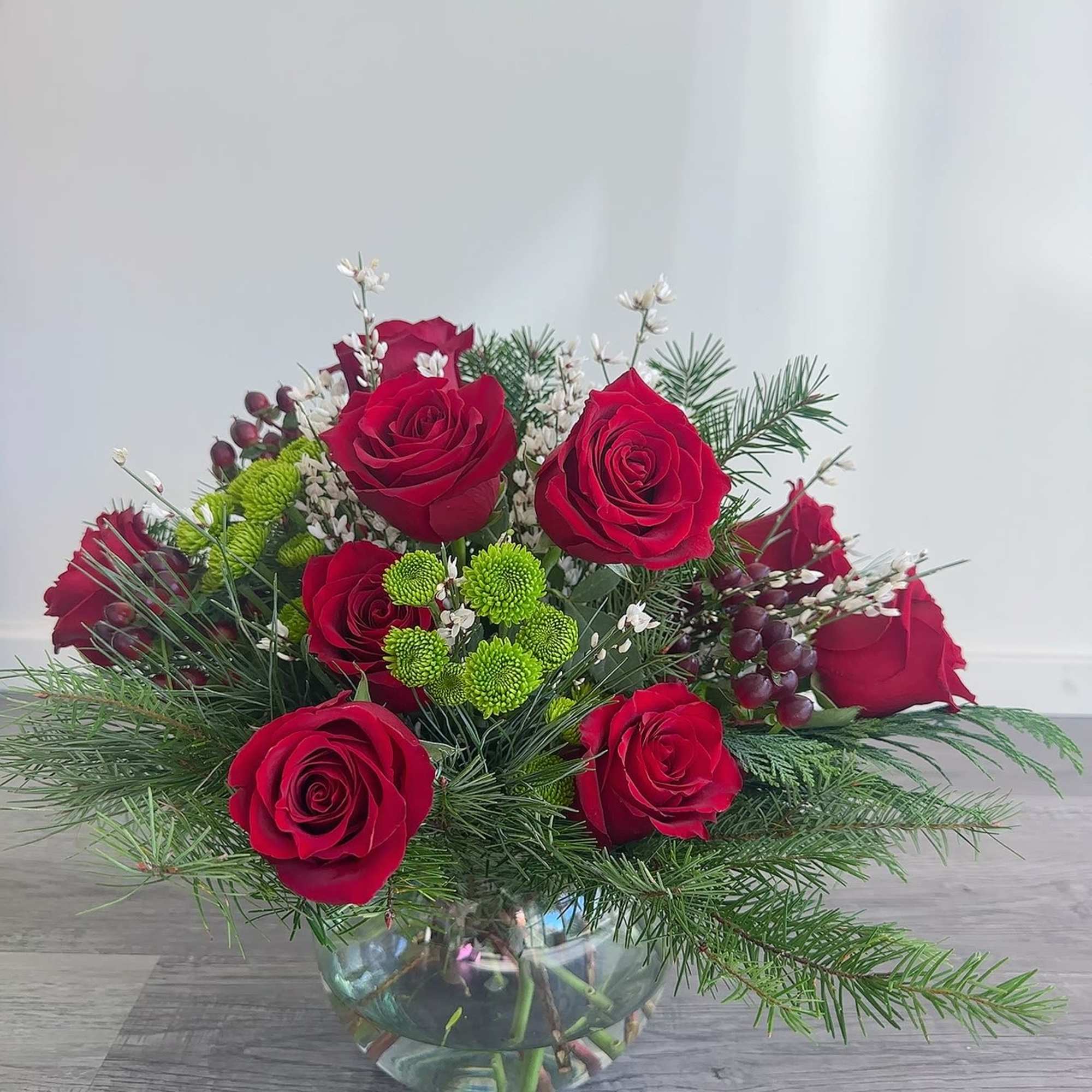 Red roses and green button mums in a glass bowl vase
