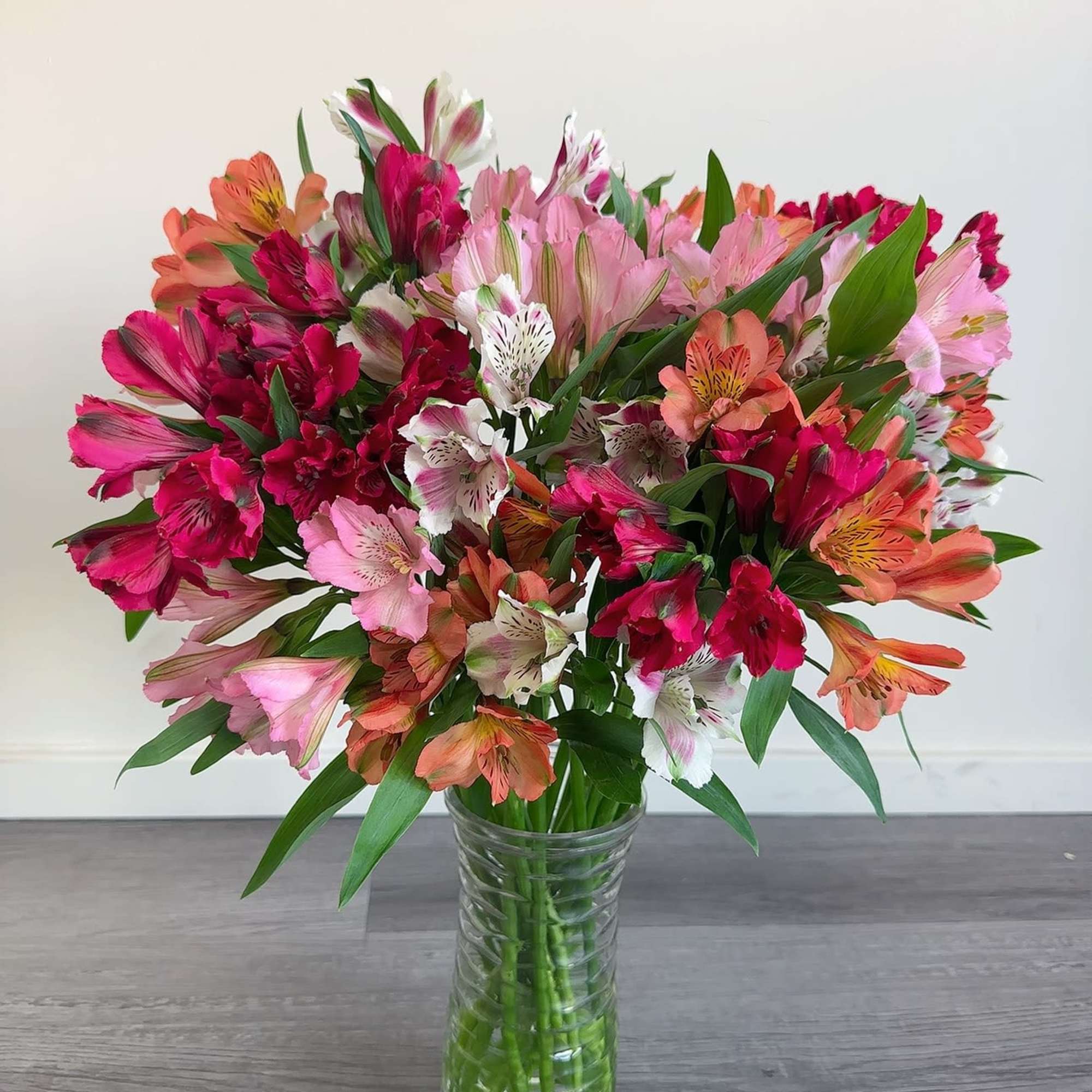 Mixed pink and orange flowers arranged in a clear glass vase