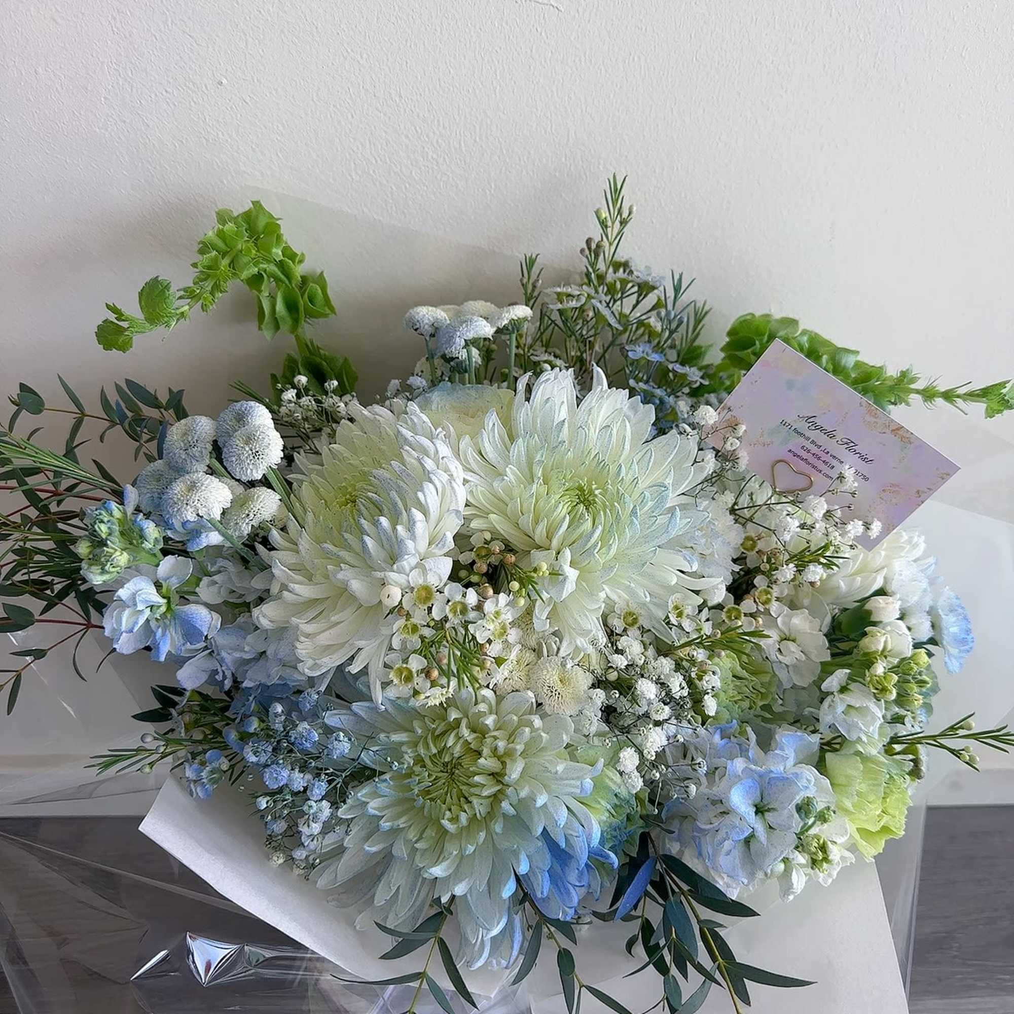 Bouquet of white and pale blue flowers wrapped in white paper