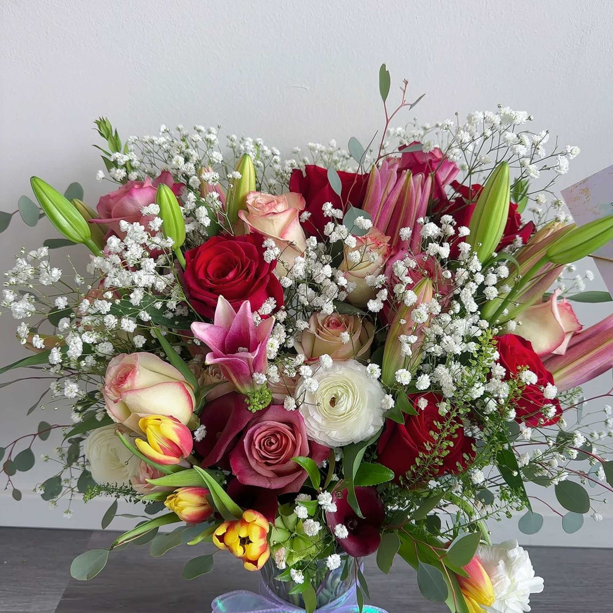 Mixed bouquet of roses, lilies, and baby's breath in a glass vase