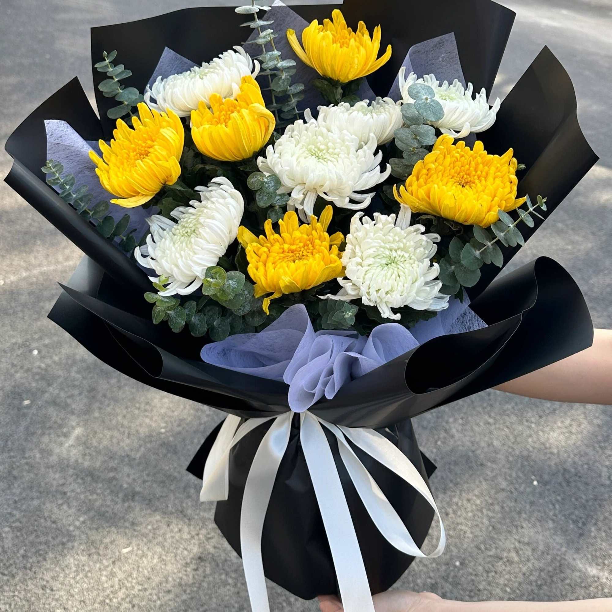 Bouquet of yellow and white chrysanthemums wrapped in black paper